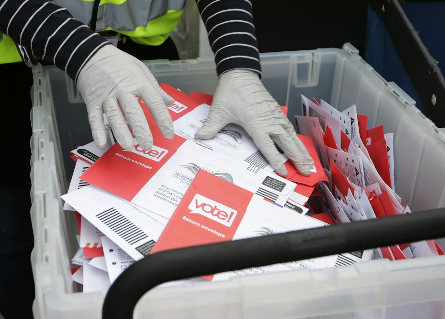 FILE - In this March 10, 2020, file photo wearing gloves, a King County Election worker collect ballots from a drop box in the Washington State primary in Seattle. Washington is a vote by mail state. A new poll from The Associated Press-NORC Center for Public Affairs Research finds Democrats are now much more likely than Republicans to support their state conducting elections exclusively by mail, 47% to 29%. (AP Photo/John Froschauer, File)