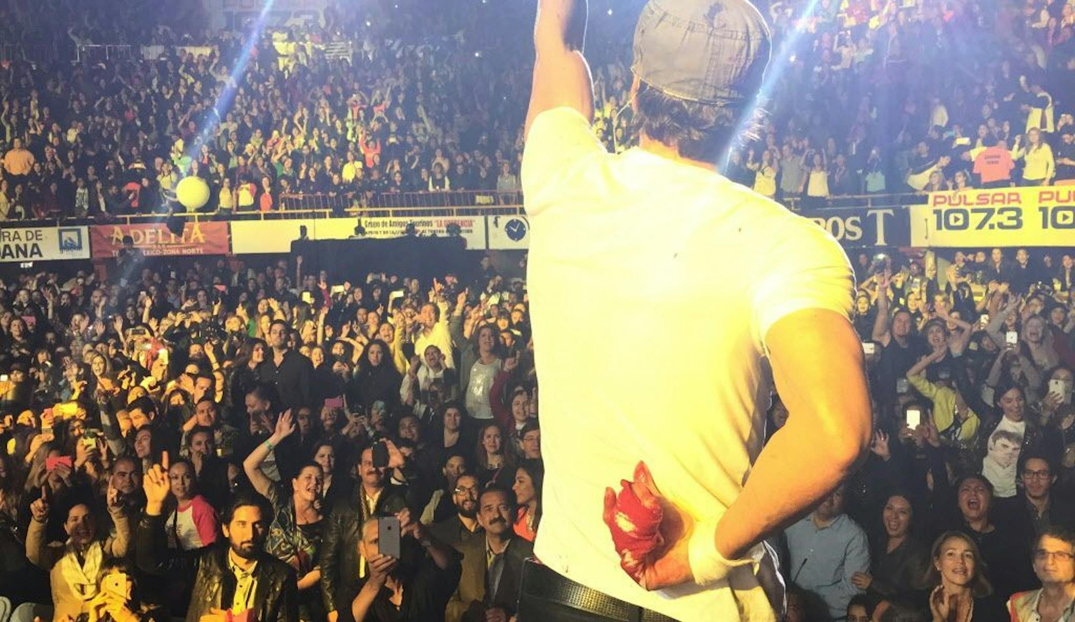 Enrique Iglesias performs while holding his bloodied and bandaged right hand behind his back during a concert in Tijuana, Mexico on Saturday, May 30, 2015.