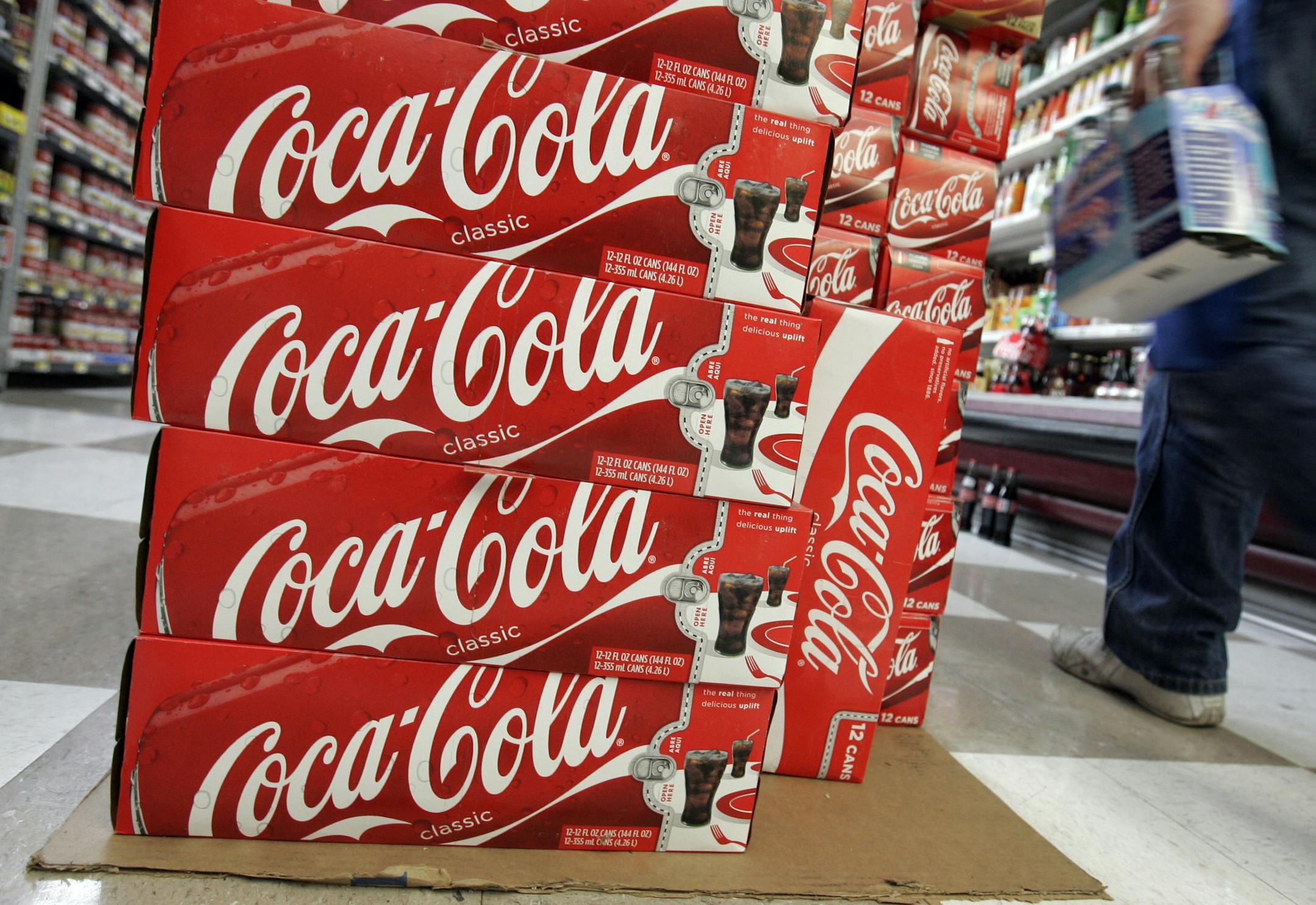 FILE- In this April 20, 2009, file photo, a customer walks by cases of Coca-Cola at JJ&F Market in Palo Alto, Calif. Coca-Cola, the world's biggest soft drink maker said Thursday, June 14, 2012, it will start doing business in Myanmar as soon as the U.S. government issues a license allowing American companies to make such investments, the first time in 60 years. (AP Photo/Paul Sakuma, file)