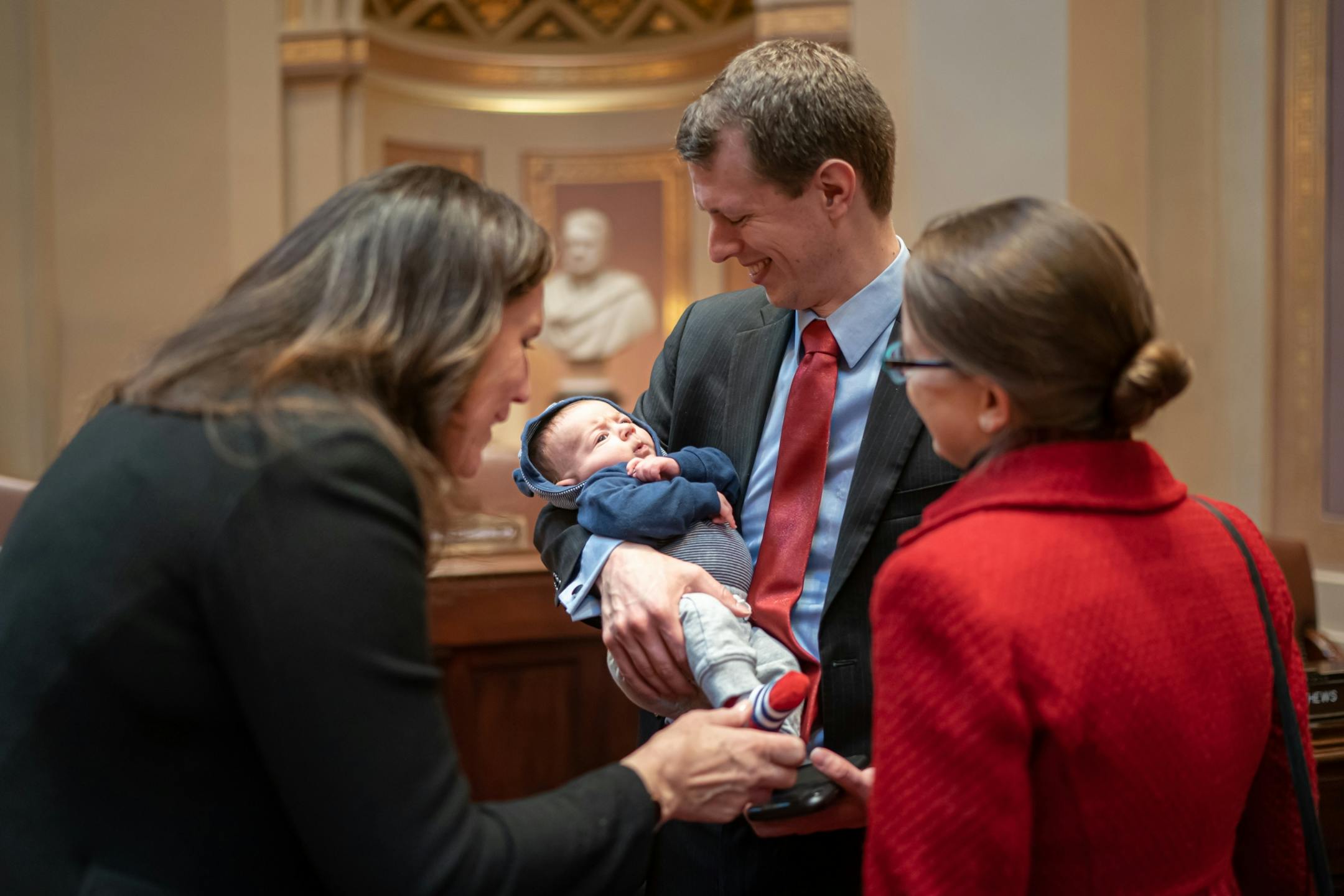 Sen. Andrew Mathews, R-Milaca held his two-month-old son Daniel on the Senate floor and Sen. Julie Rosen, R-Vernon Center couldn't resist wiggling Daniel's toes. On the right is Daniel's mom, and Andrew's wife, Elsa.