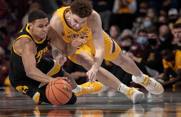 Iowa Hawkeyes forward Keegan Murray (15) left and Minnesota Gophers forward Jamison Battle (10) dive for a loose ball in the second half , the Gophers