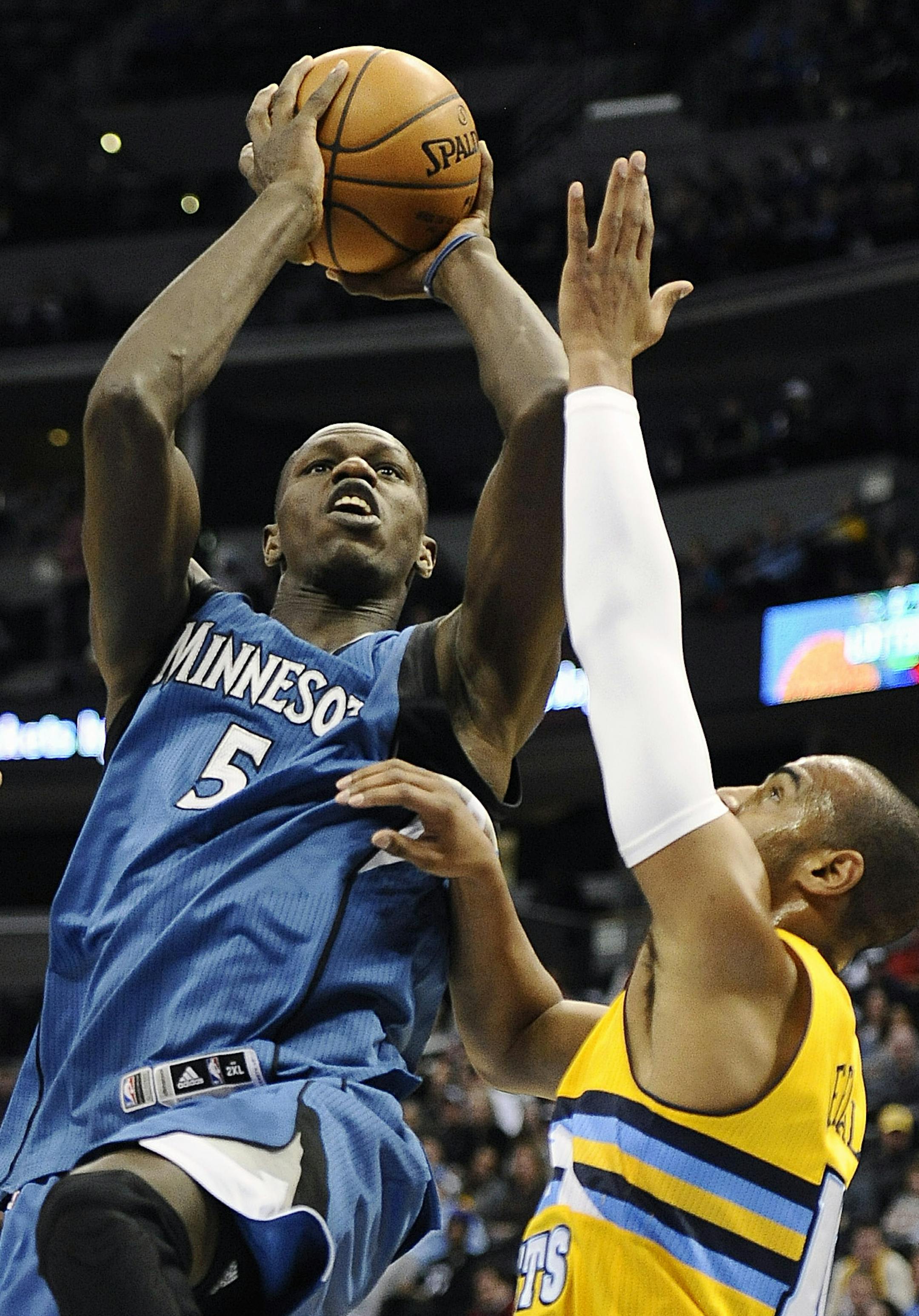 Minnesota Timberwolves center Gorgui Dieng, center, shoots between Denver Nuggets center Timofey Mozgov, left, and guard Arron Afflalo duirng the first half of an NBA basketball game Friday, Dec. 26, 2014 in Denver. (AP Photo/Chris Schneider)
