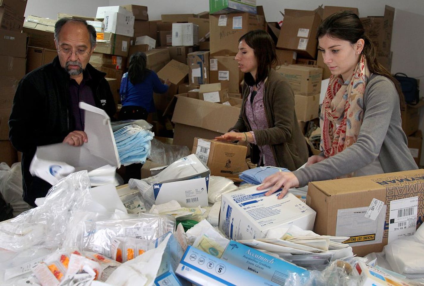 Segundo Valesquez, left, helped his staff Dana Dallavalle, center, and Alison Cerve sorted medical supplies donated to his "Mano a Mano" foundation.