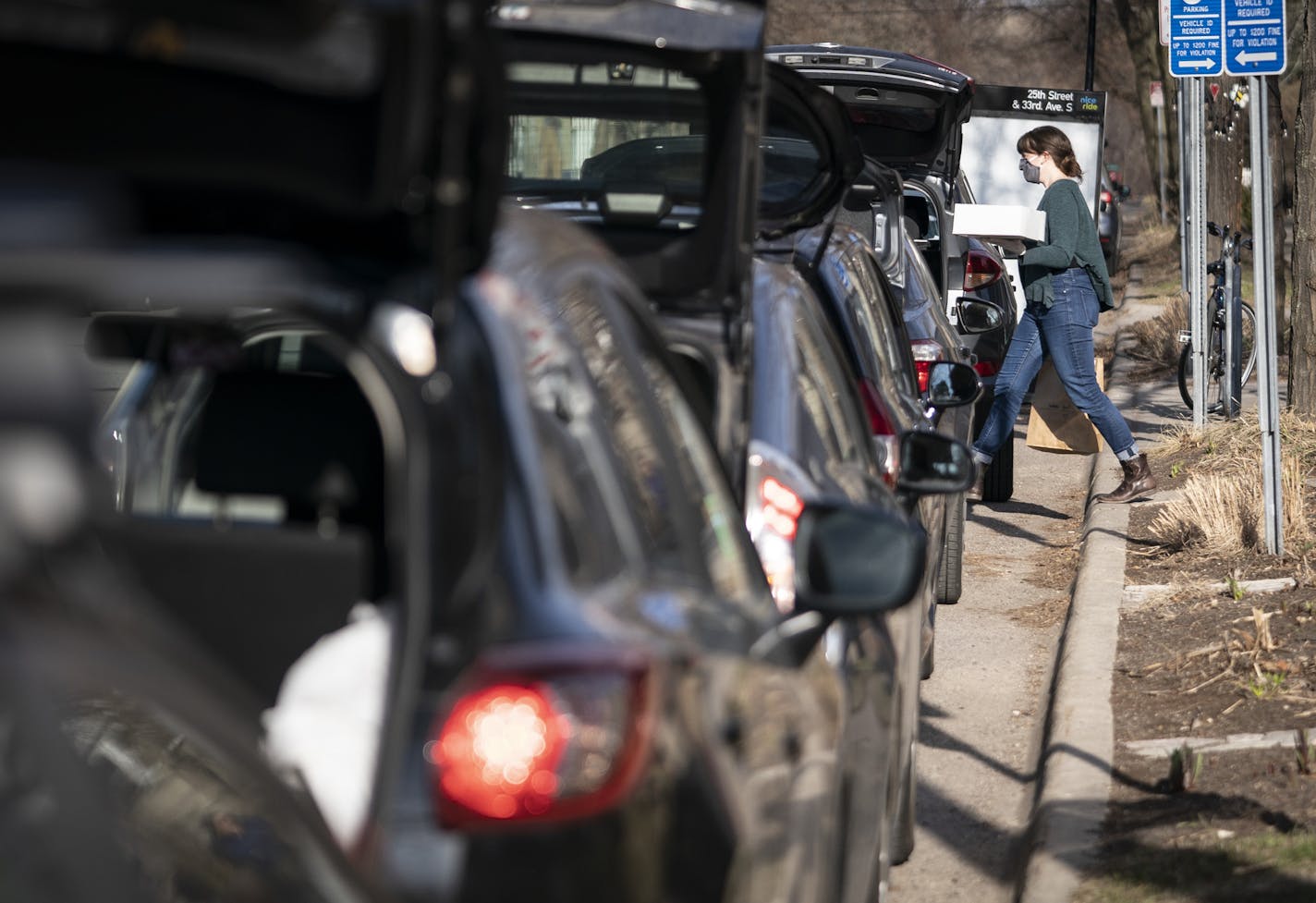 Keelie Ritter delivered an order to a trunk as cars lined the street in front of the Birchwood Cafe for take out orders as the restaurant sold out of it's Friday fish fry in Minneapolis, Minn., on Friday, April 10, 2020. ] RENEE JONES SCHNEIDER &#xa5; renee.jones@startribune.com