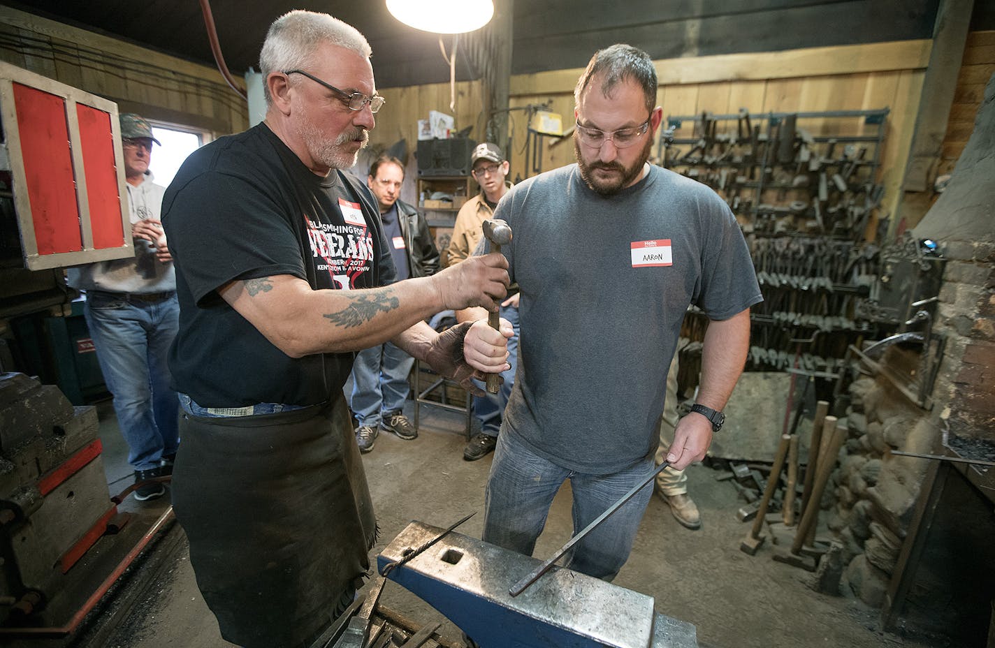 Ken Zitur, left, of Ken's Custom Iron, gave a lesson in blacksmithing to a group of military veterans, including Army Veteran Aaron Othoudt, cq, of Foley, in his shop, Friday, November 10, 2017 in Avon, MN. ] ELIZABETH FLORES &#xef; liz.flores@startribune.com