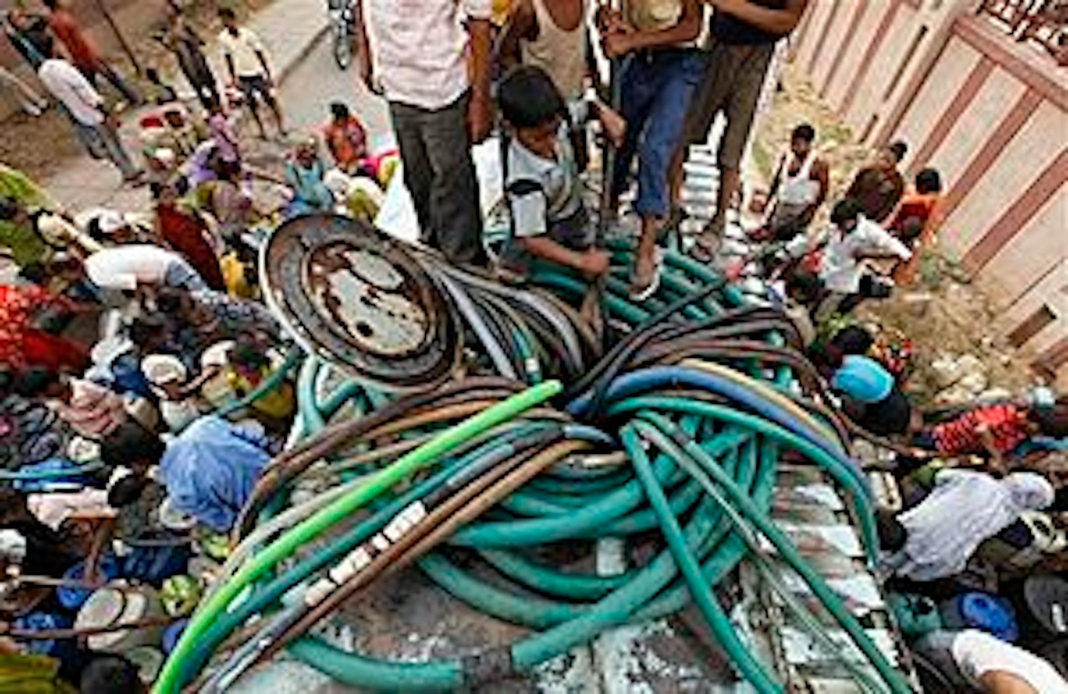 Indian slum dwellers collect drinking water from a mobile water tanker in New Delhi, India, Thursday, May 27, 2010. A drinking water shortage and power outages are adding to the woes of locals as severe heat conditions continue in northern, western and central India. (AP Photo/Mustafa Quraishi)
