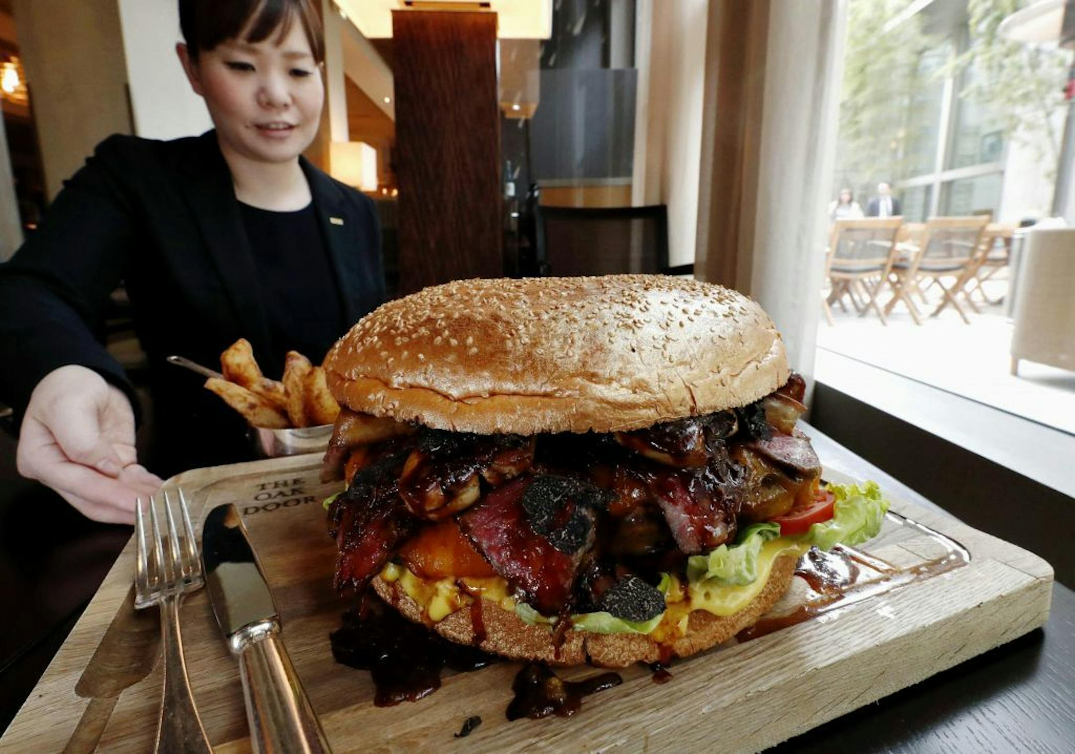 In this Thursday, March 28, 2019, photo, a "golden giant burger" is served at a restaurant of Hotel Grand Hyatt Tokyo in Tokyo. The $900 wagyu (Japanese-produced beef) burger was unveiled to commemorate the era change. What's in a name? Quite a lot if you're a Japanese citizen awaiting the official announcement Monday, April 1, 2019 of what the soon-to-be-installed new emperor's next era will be called. It's a proclamation that has happened only twice in nearly a century, and the new name will f