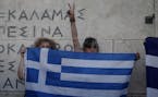 Anti-austerity protesters hold a Greek flag during a rally against the government's agreement with its creditors in front of the tomb of the unknown s