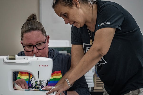 Beth Seidl works on a ribbon shirt with help from regalia artist Fawn Youngbear-Tibbetts. 