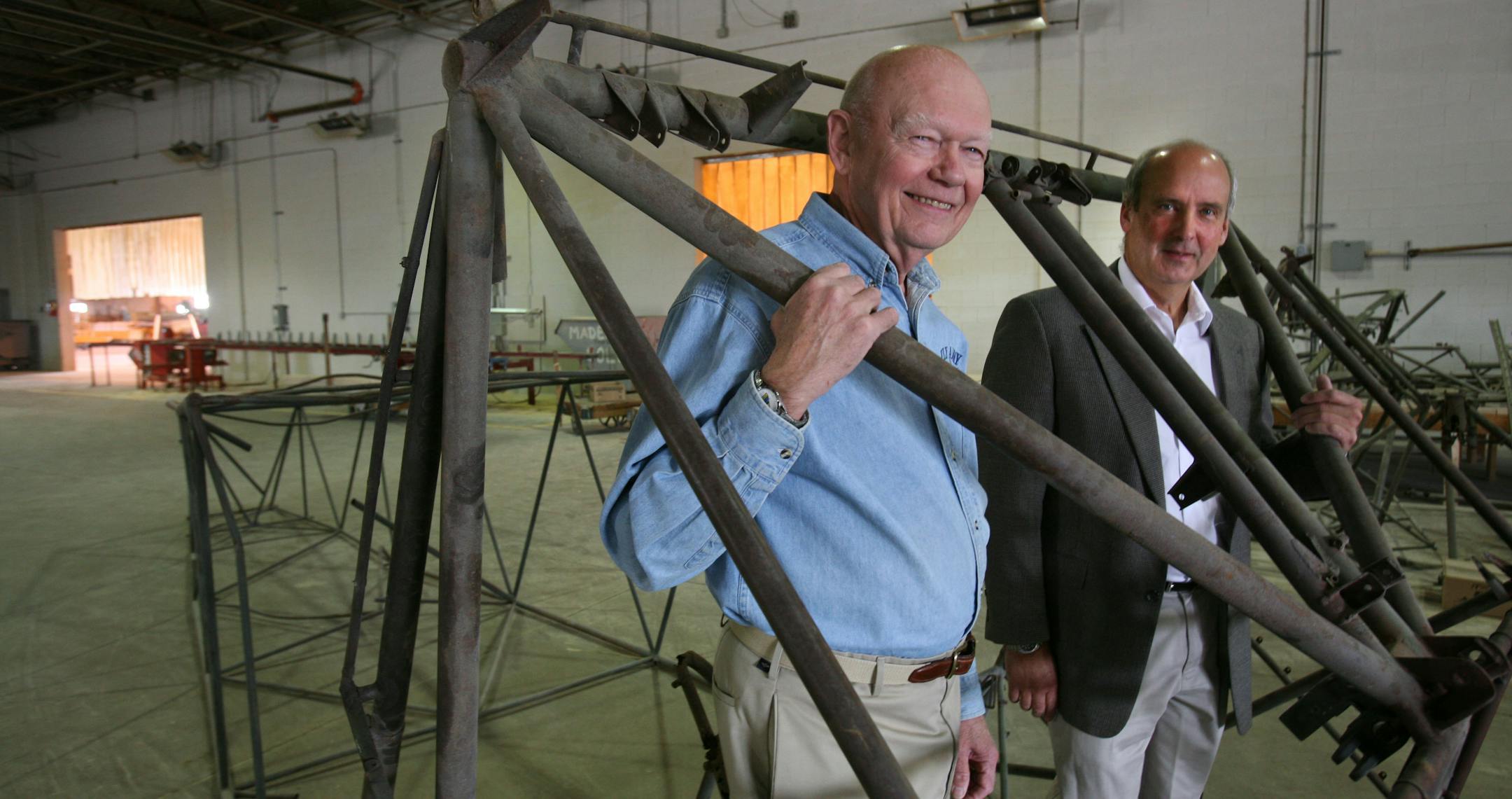 John James, left, and Nick Linsmayer, CEO of Villaume Industries Inc., showed part of the skeleton of a WWII glider. The company made the original wooden parts to the gliders and, with the help of James and others, is planning to rebuild this one.