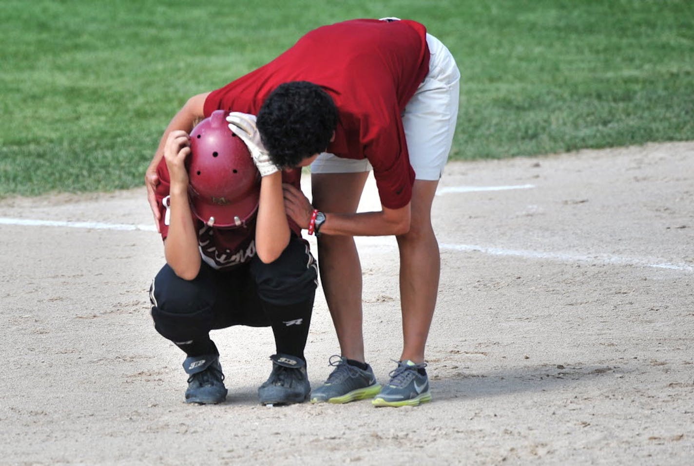 Maple Grove assistant coach Pam Hennen helped Taylor Bratten after she made the last out in the team's 6-2 loss to Stillwater in the Class 3A championship game on June 8 in North Mankato. The top-ranked Crimson finished 23-2, including two tournament wins in which they were not scored upon. Photo by Glen Stubbe * gstubbe@startribune.com