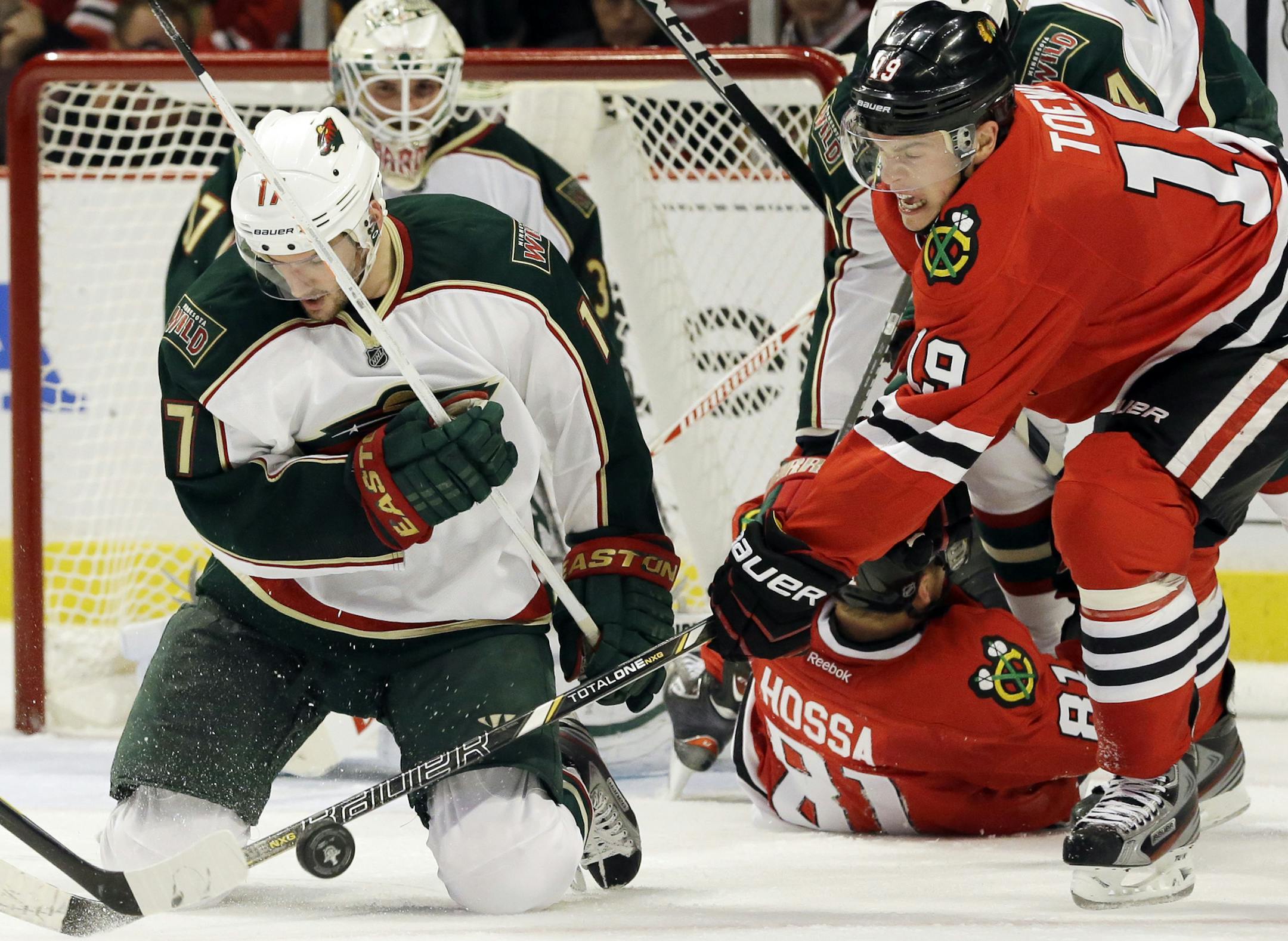 Chicago Blackhawks' Jonathan Toews (19) battles for the puck against Minnesota Wild's Torrey Mitchell (17) during the second period of Game 2 of an NHL hockey Stanley Cup first-round playoff series in Chicago, Friday, May 3, 2013. (AP Photo/Nam Y. Huh)
