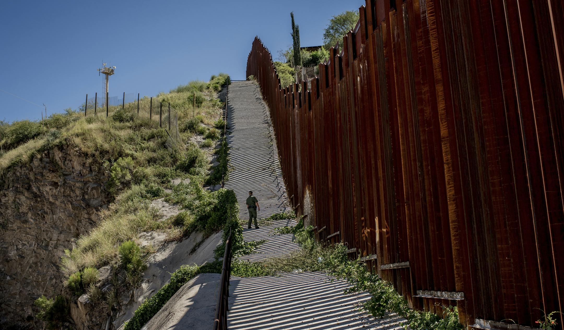FILE-- A Border Patrol agent watches from the U.S. side of the border fence in
Nogales, Ariz., Sept. 22, 2016. President-elect Donald J. Trump said on Jan. 6, 2017, that financing a border wall with taxpayer money would allow the work to begin more quickly. But he insisted that Mexico will ultimately reimburse the U.S. for its construction. (Tomas Munita/The New York Times)