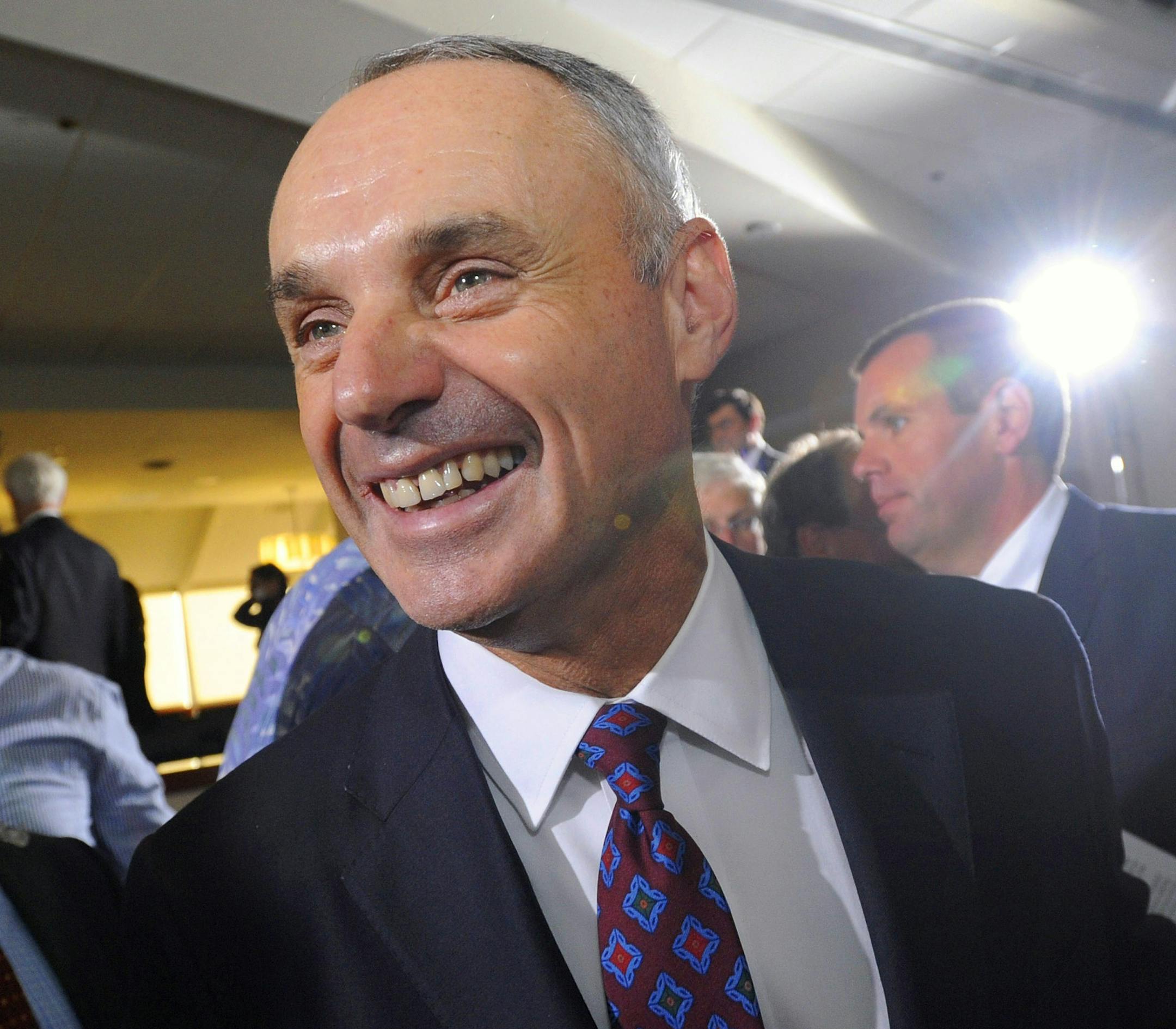 Major League Baseball Chief Operating Officer Rob Manfred, center, smiles after team owners elected him as the next commissioner of Major League Baseball during an owners quarterly meeting in Baltimore, Thursday, Aug. 14, 2014. (AP Photo/Steve Ruark)