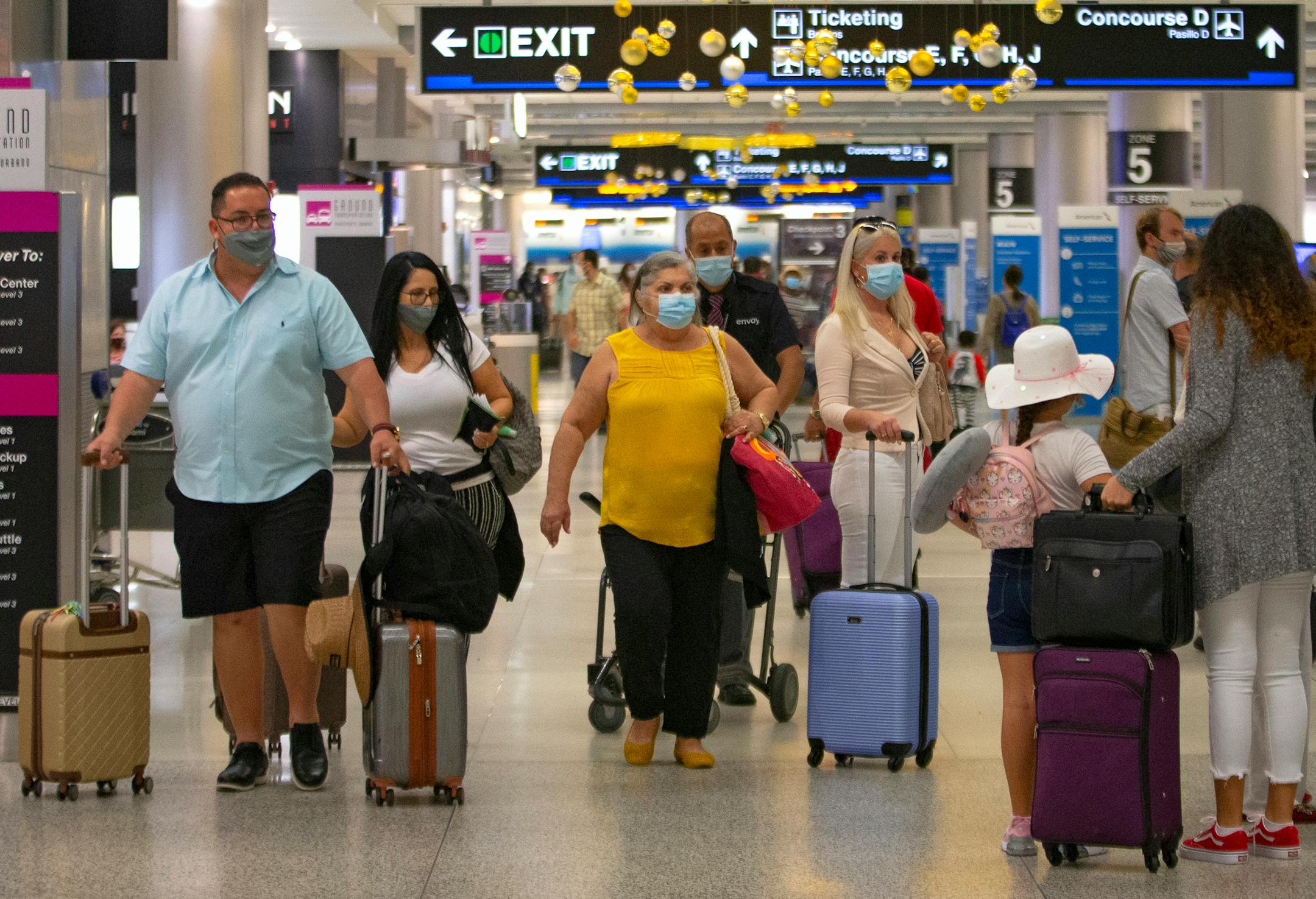 Travelers wearing protective face masks walking through Concourse D at the Miami International Airport on Sunday, November 22, 2020 in Miami, Florida. With the coronavirus surging out of control, the nation's top public health agency pleaded with Americans not to travel for Thanksgiving and not to spend the holiday with people from outside their household. (David Santiago/Miami Herald/TNS) ORG XMIT: 1843894