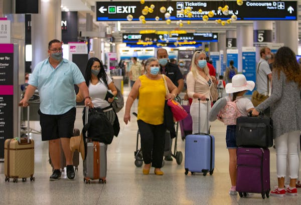 Travelers wearing protective face masks walking through Concourse D at the Miami International Airport on Sunday, November 22, 2020 in Miami, Florida.