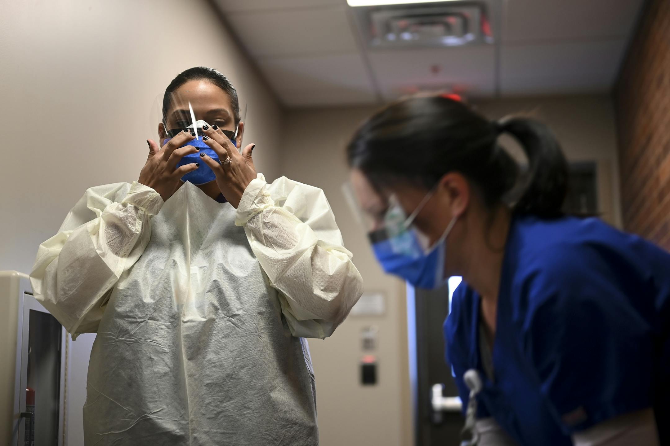 M Health Fairview Medical Assistants Reece Wallaker, left, and Sandy Graves, put on protective equipment prior to Tuesday's demonstration on drive-up COVID-19 testing.