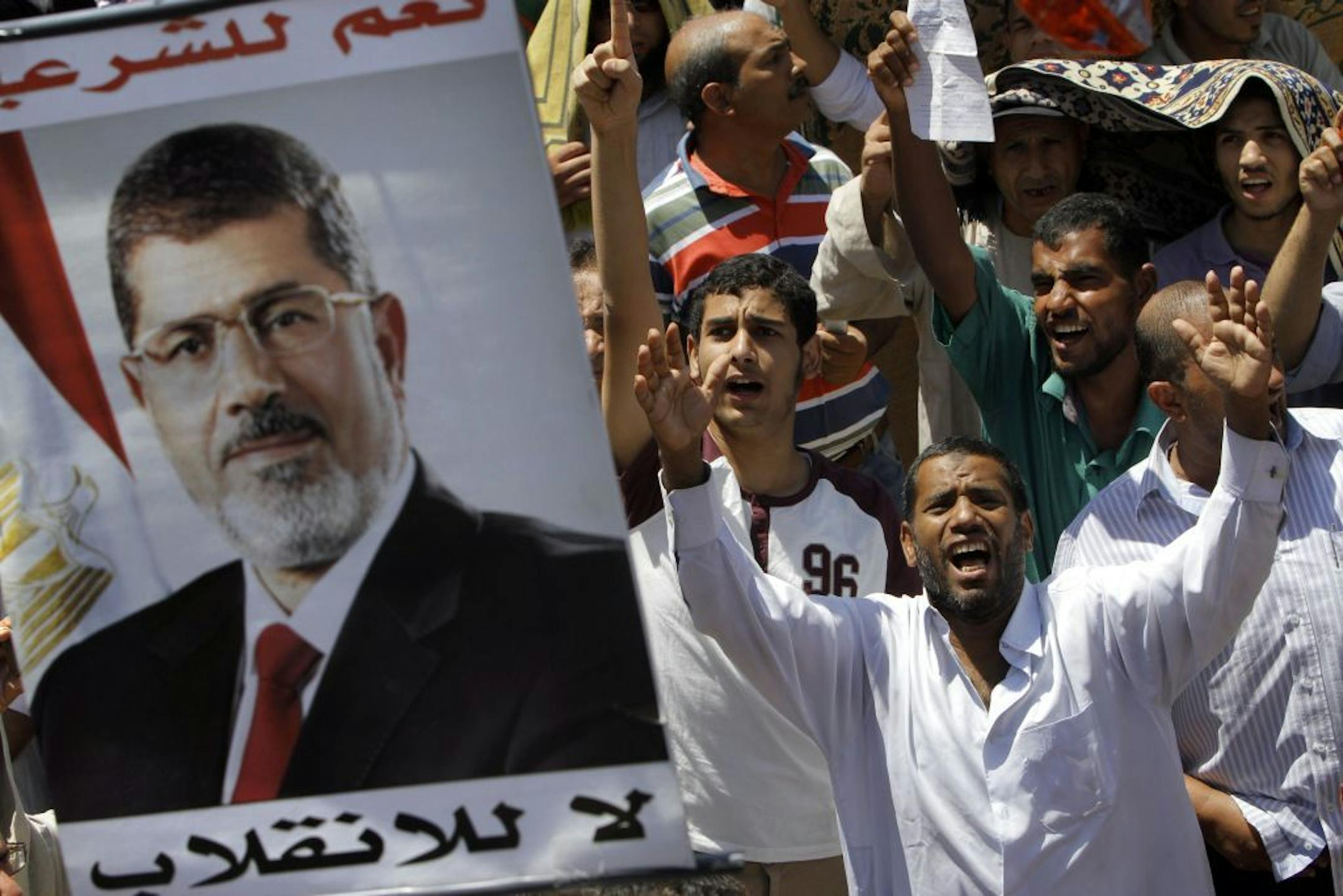 Supporters of Egypt's ousted President Mohammed Morsi shout slogans under his poster following Friday prayers in Nahda square, where protesters installed their camp near Cairo University in Giza, southwest of Cairo, Egypt, Friday, Aug. 9, 2013.