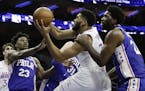 Minnesota Timberwolves' Karl-Anthony Towns, center, tries to get a shot past Philadelphia 76ers' Joel Embiid, right, and Jimmy Butler during the first
