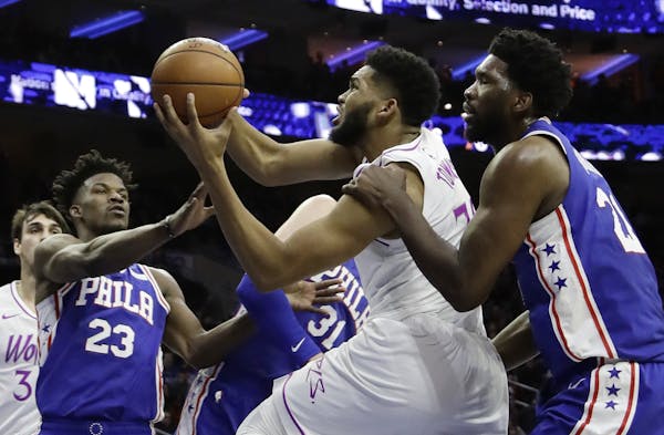 Minnesota Timberwolves' Karl-Anthony Towns, center, tries to get a shot past Philadelphia 76ers' Joel Embiid, right, and Jimmy Butler during the first