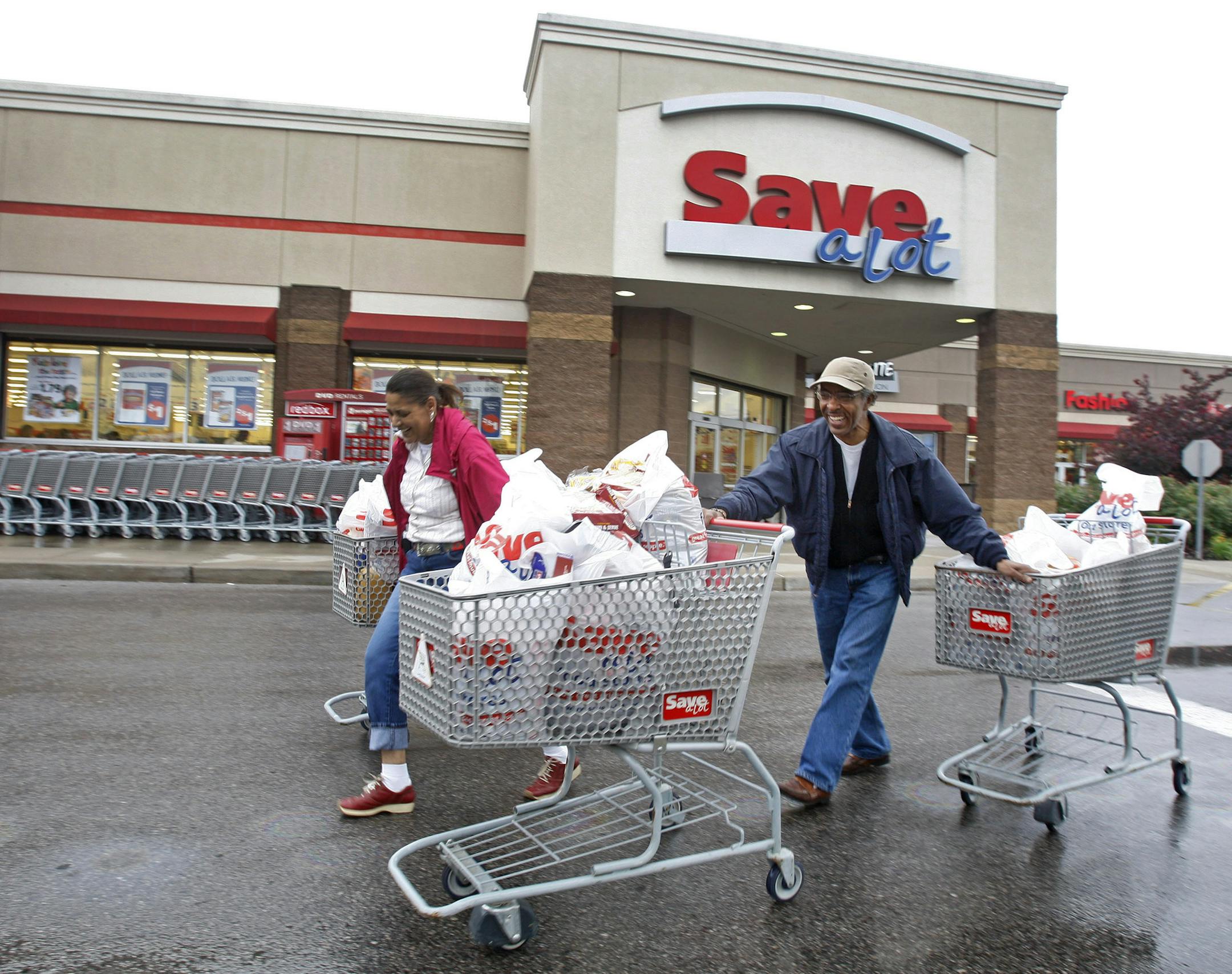 Shoppers Camelious Thompson and her brother Mark Eaton leave a Save-A-Lot store in St. Louis, Missouri, U.S., on Thursday, May 20, 2010. Supervalu Inc.'s Save-A-Lot unit, a discount grocer specializing in store-brand products, plans to expand in urban areas to fill in gaps left after larger chains moved to the suburbs. Photographer: Peter Newcomb/Bloomberg *** Local Caption *** Camelious Thompson; Mark Eaton ORG XMIT: MIN2012120516120005