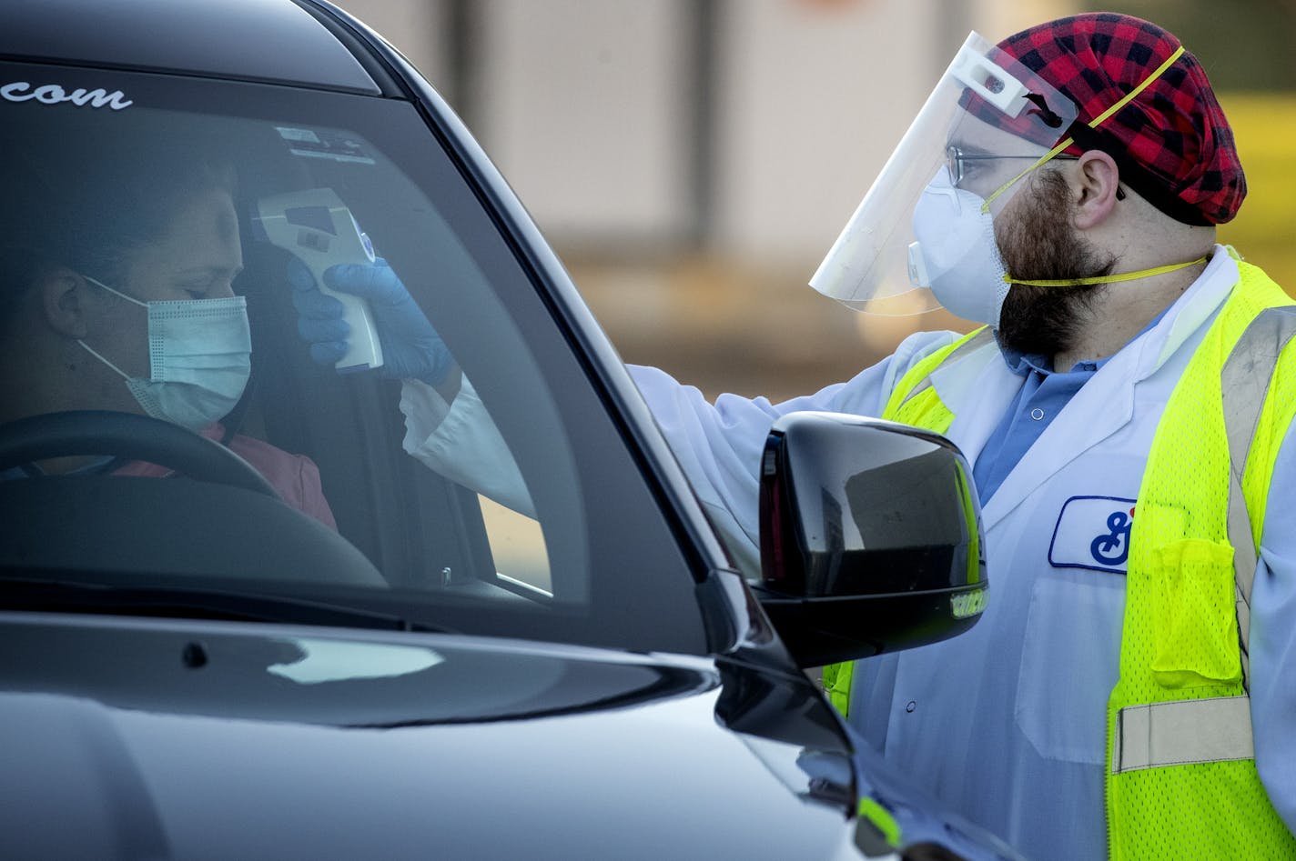 Scott Ross checked the temperatures of employees and visitors at the entry gate at General Mills in Chanhassen.