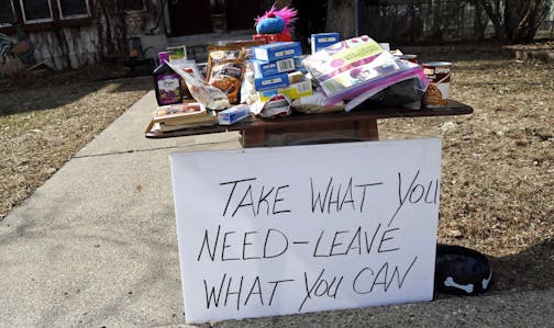 Food for the taking and an invitation to leave food is in front of a south Minneapolis home Monday, March 23, 2020 as Minnesotans care for others during the effort to slow down the coronavirus in the state. (AP Photo/Jim Mone)