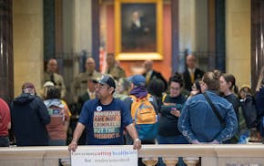 Leonel Mejia shows his views on immigrant healthcare during a vigil outside of House chambers at the Minnesota State Capitol on Friday.