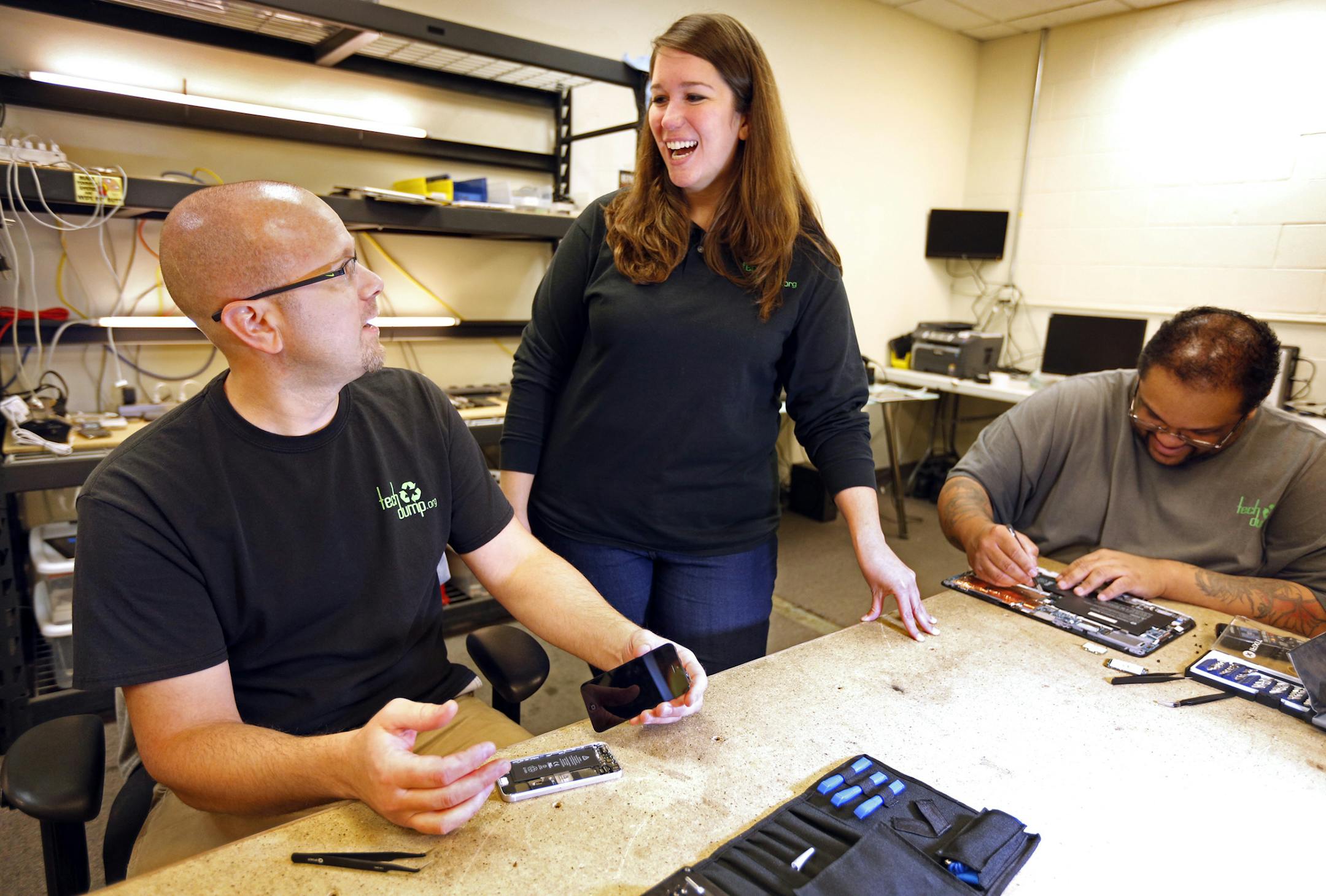 Tech Dump CEO Amanda LaGrange (center) chats with technicians Dan Saba (left) and Alonzo Nelson (right) as they work on refurbishing an iPhone and computer board. Consumer technology commands much higher prices in the resale market than recycling the metals, glass and plastics. Those commodity prices have been down for nearly two years, causing some competitors to retrench or fail. ] brian.peterson@startribune.com
Golden Valley, MN - 09/09/2016