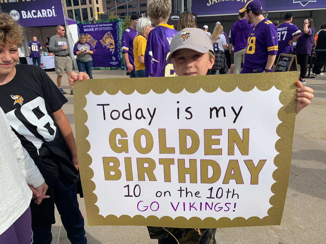 Marshall Spaeth, who turned 10 on Sunday, carries a sign announcing the occasion while his brother Landan, 11, looks on outside US Bank Stadium.
