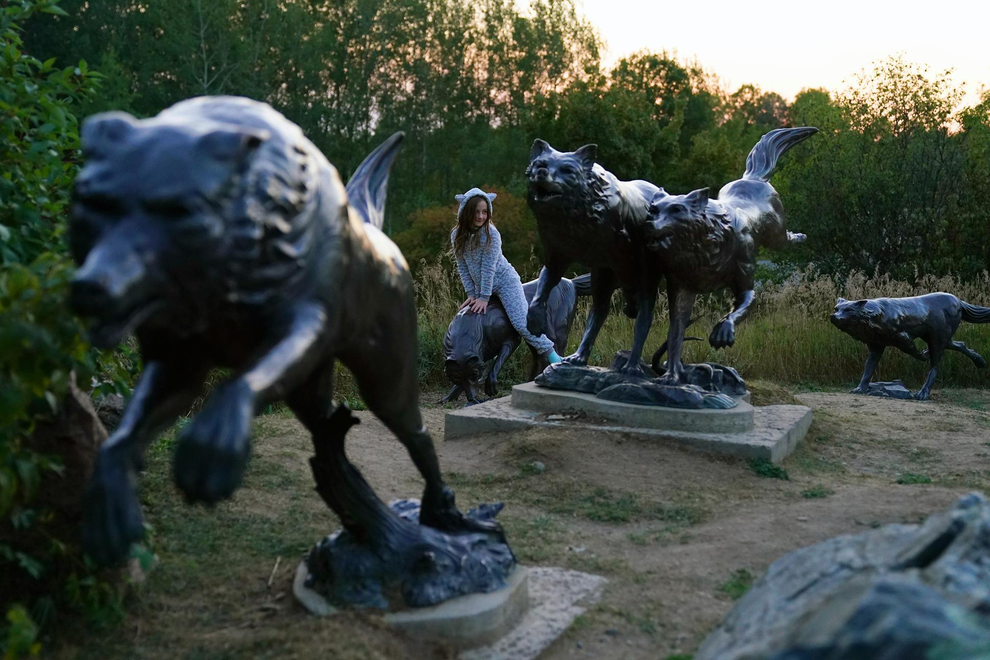 A girl in a wolf suit rides one of the statues at the International Wolf Center.