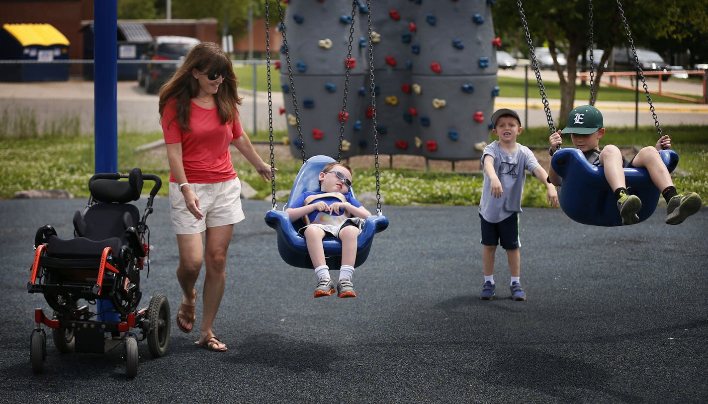 Suzanne Sullivan pushed her son Dermot 8 in a swing as her other son Ryan 6, pushed his brother Owen, 10 during outing in the park. .Dermot has a mitochondrial disorder but is able to play with his two brothers on an inclusive playground at Alice Smith Elementary Monday June 23, 2014 in Hopkins, MN. ] Jerry Holt Jerry.holt@startribune.com