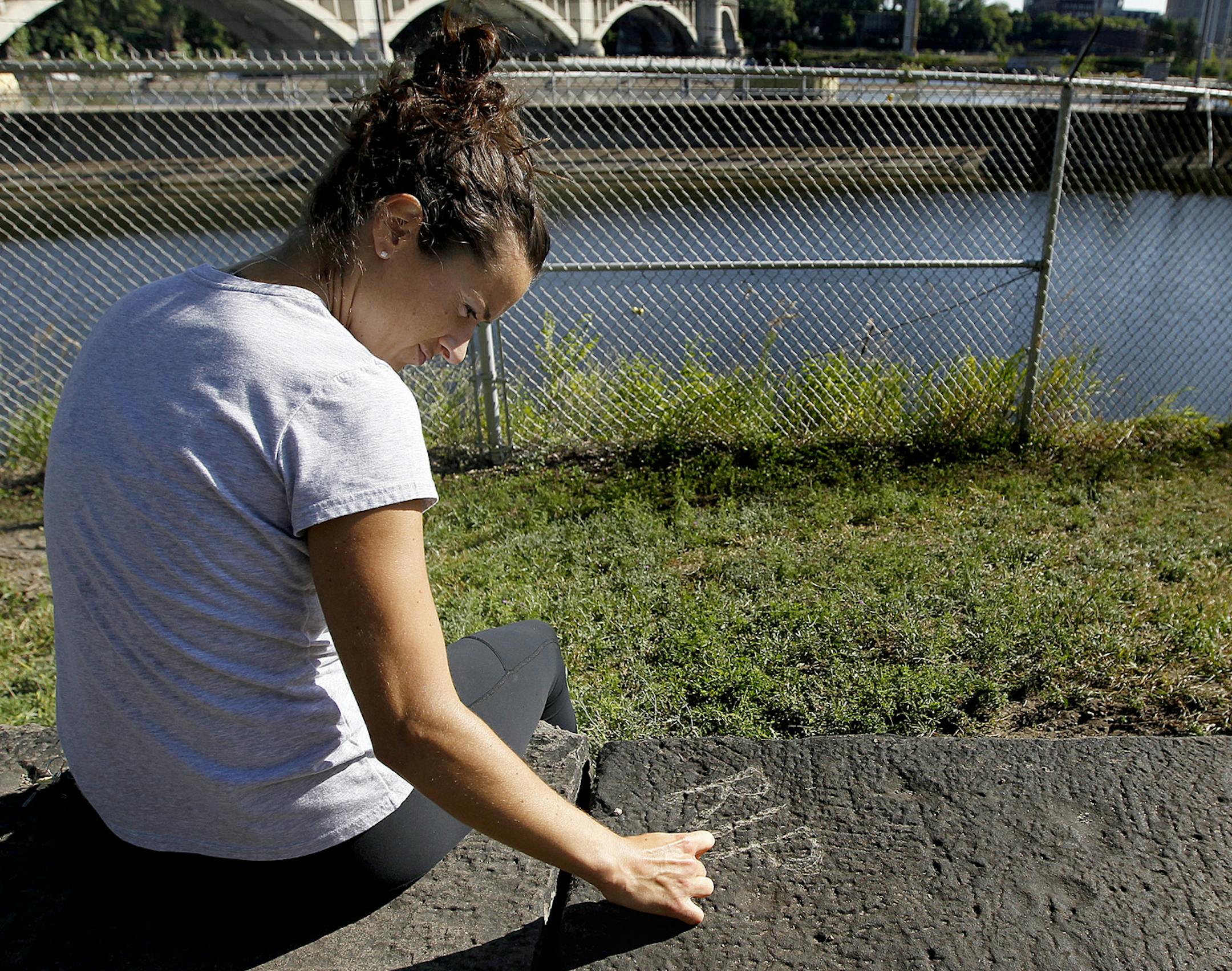 Emily Peterson of Minneapolis scribbled "R.I.P." onto an area near the scene where one man died when the vehicle he was driving plunged into the Mississippi River near the Stone Arch Bridge, Tuesday, August 13, 2013. Peterson, who lives in a nearby building said she heard a large crash last night from her balcony. (ELIZABETH FLORES/STAR TRIBUNE) ELIZABETH FLORES • eflores@startribune.com