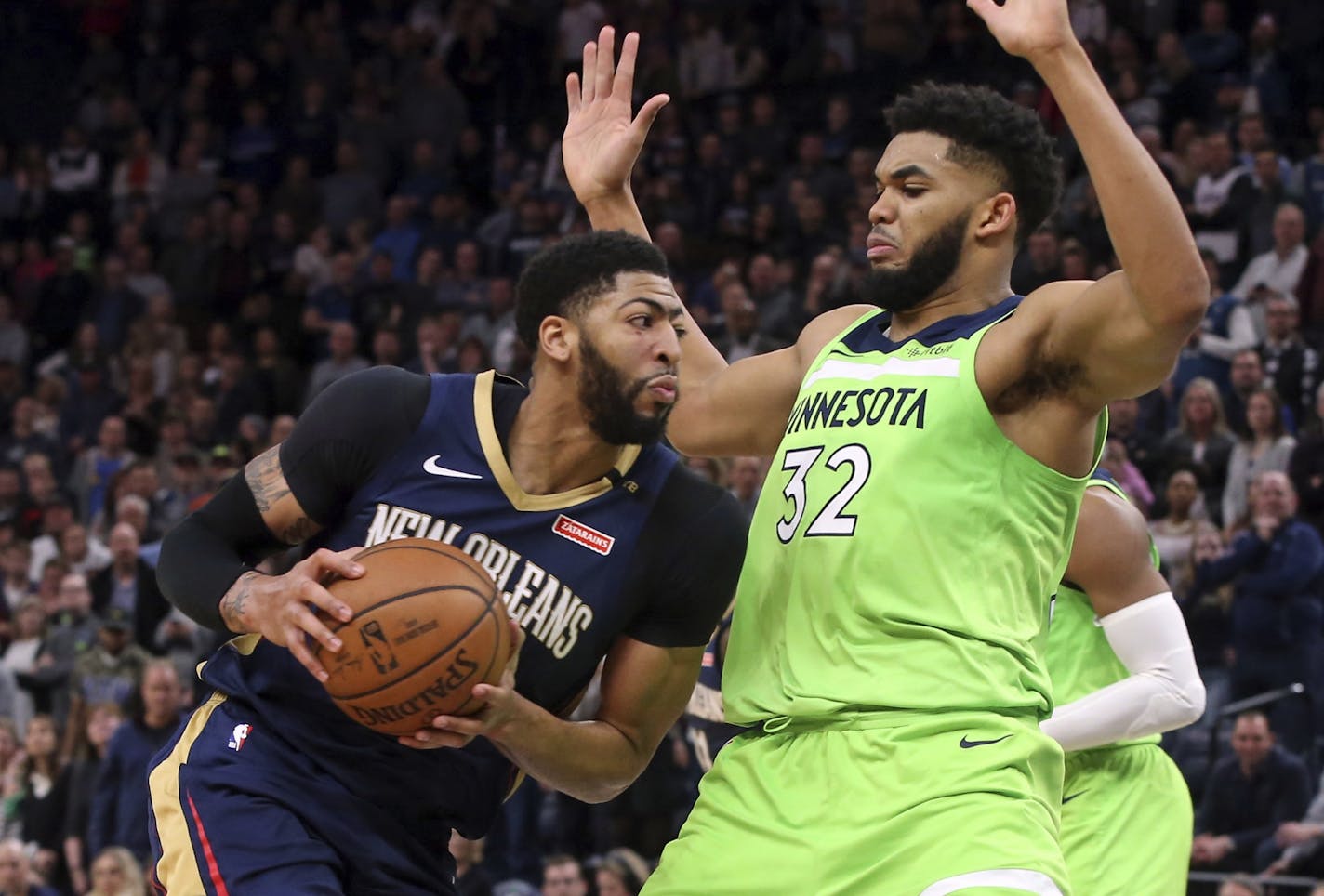 New Orleans Pelicans' Anthony Davis, left, drives as Minnesota Timberwolves' Karl-Anthony Towns defends in the second half of an NBA basketball game Saturday, Jan. 12, 2019, in Minneapolis.