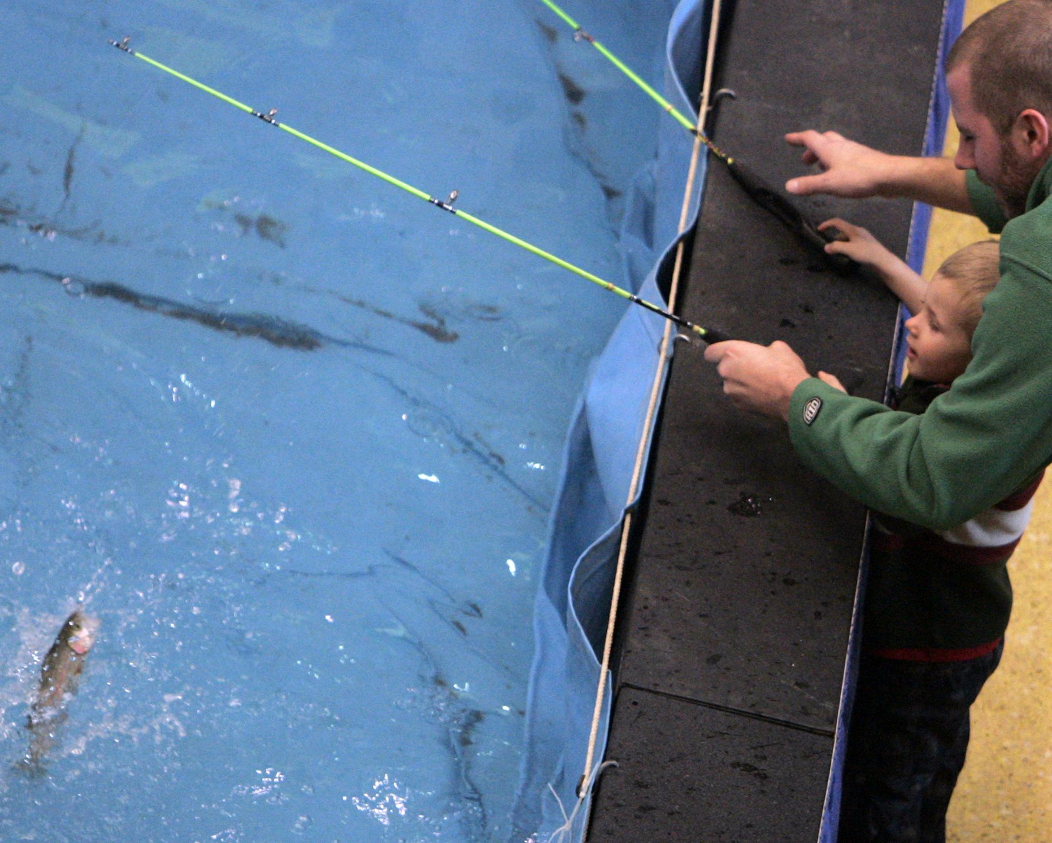 DAVID JOLES * djoles@startribune.com St. Paul, MN - Jan. 13, 2010- The Minnesota Sportsmen's Boat, Camping and Vacation Show opened Wednesday at the River Centre and will run through Jan. 17. Here, Jaxson Benson, 2, pulls in a rainbow trout with help from his dad Chris of Eden Prairie at the trout pond as the father and son took in the Sportsmen's Show. The duo caught six trout and took them home to eat. ORG XMIT: MIN2015010819522815