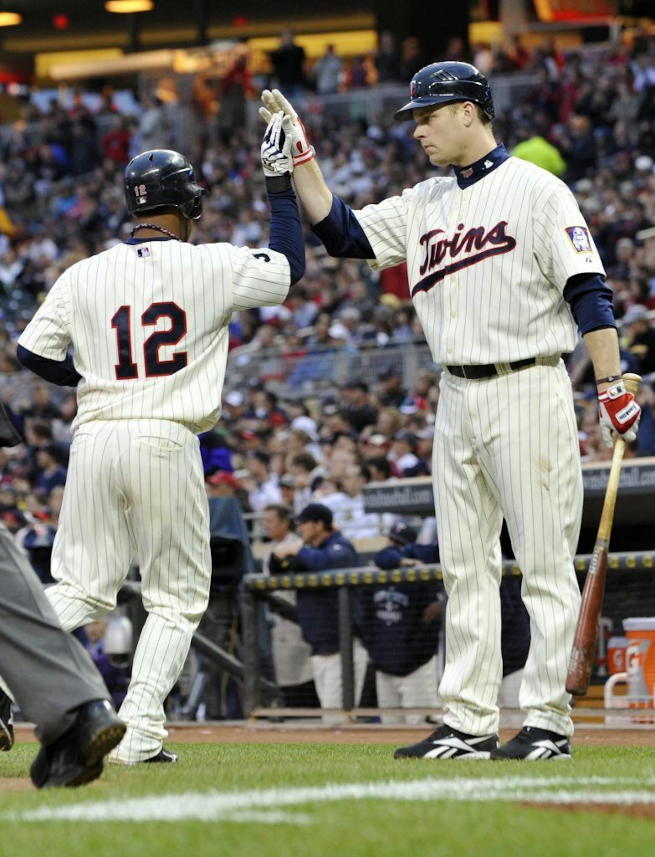 Minnesota Twins' Alexi Casilla, left, is greeted by teammate Justin Morneau after scoring on a single by Jason Kubel off Los Angeles Angels' Tyler Chatwood in the third inning of a baseball game on Friday, May 27, 2011, in Minneapolis.