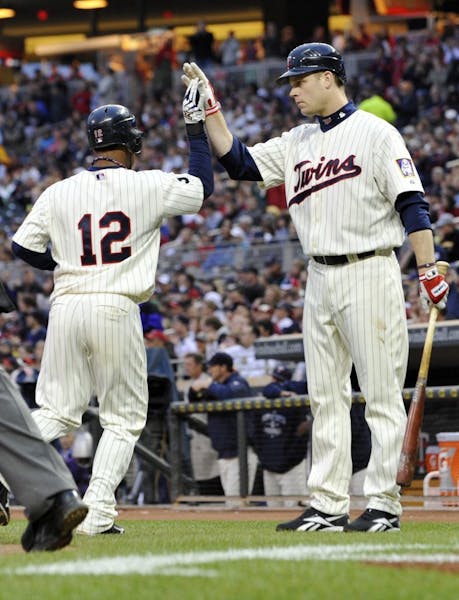 Minnesota Twins' Alexi Casilla, left, is greeted by teammate Justin Morneau after scoring on a single by Jason Kubel off Los Angeles Angels' Tyler Cha