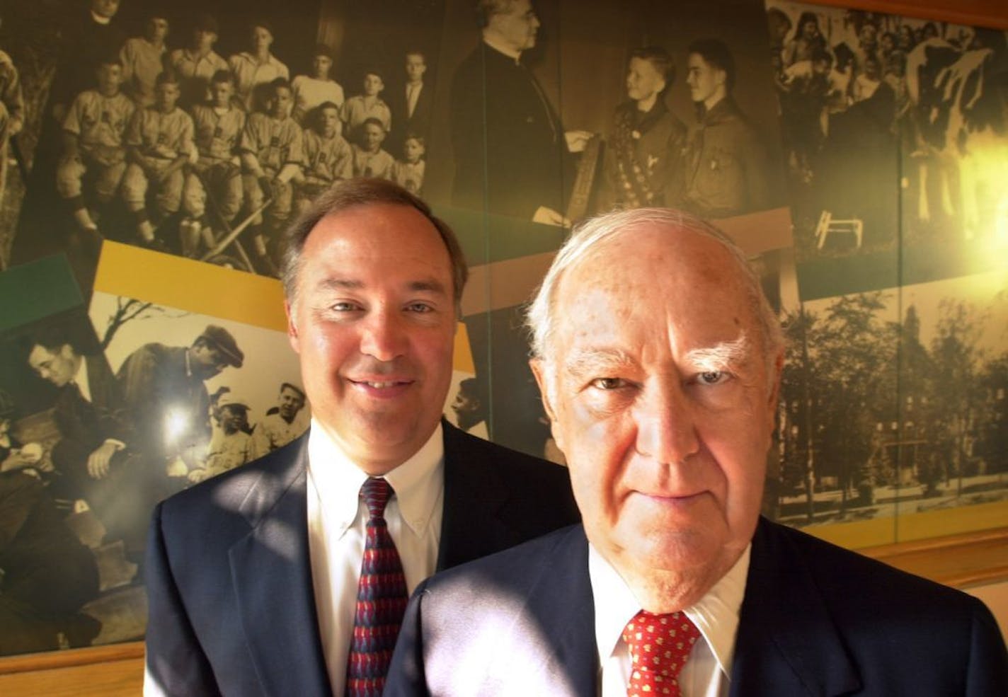 Minneapolis, MN, Thursday, August 14, 2003 -- Mark Rauenhorst, chief executive of Opus Corp, left, and Gerry Rauenhorst, founding chair, right stand in front of historic photos from St. Joseph's Home for Children's past. Including Babe Ruth, Rin-tin-tin, and a nun who could squirt kids while she milked a cow at the state fair. Opus is donating a several-hundred thousand dollar renovation of living quarters as part of its 50th birthday celebration, and in keeping with the company's tradition of d