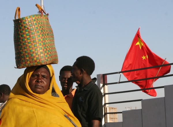 ** ADVANCE TO GO WITH STORY EU REDISCOVERS AFRICA **A Sudanese woman walks past a Chinese flag on a street in Khartoum, in this Thursday Feb. 1, 2007 