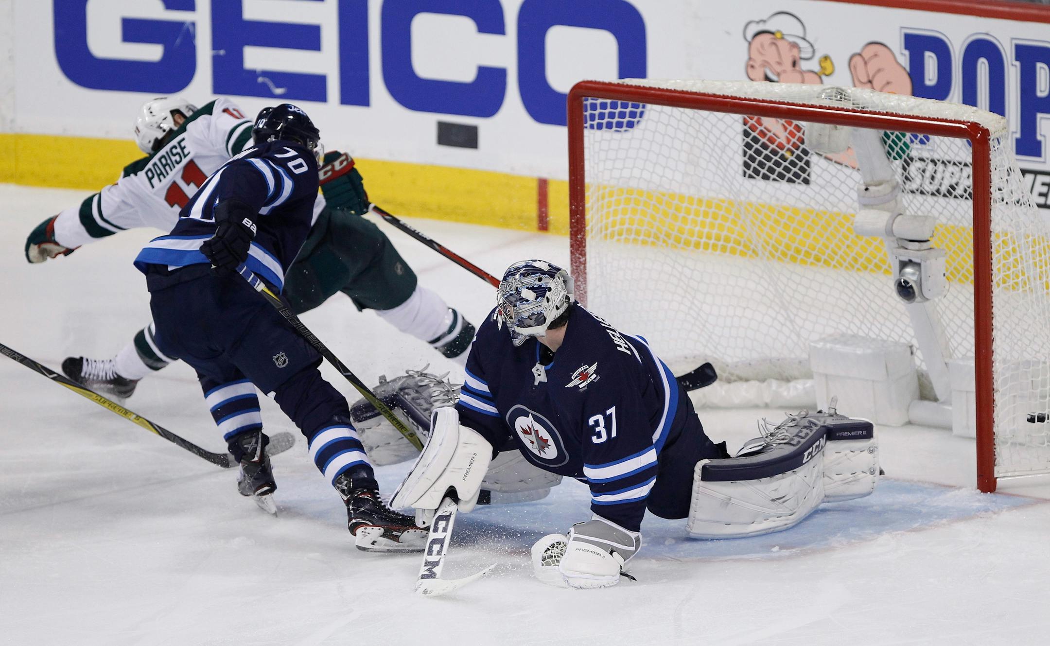 Minnesota Wild's Zach Parise (11) scores on Winnipeg Jets goaltender Connor Hellebuyck (37) as Joe Morrow (70) defends during the third period of Game 1 in an NHL hockey first-round playoff series Wednesday, April 11, 2018, in Winnipeg, Manitoba.