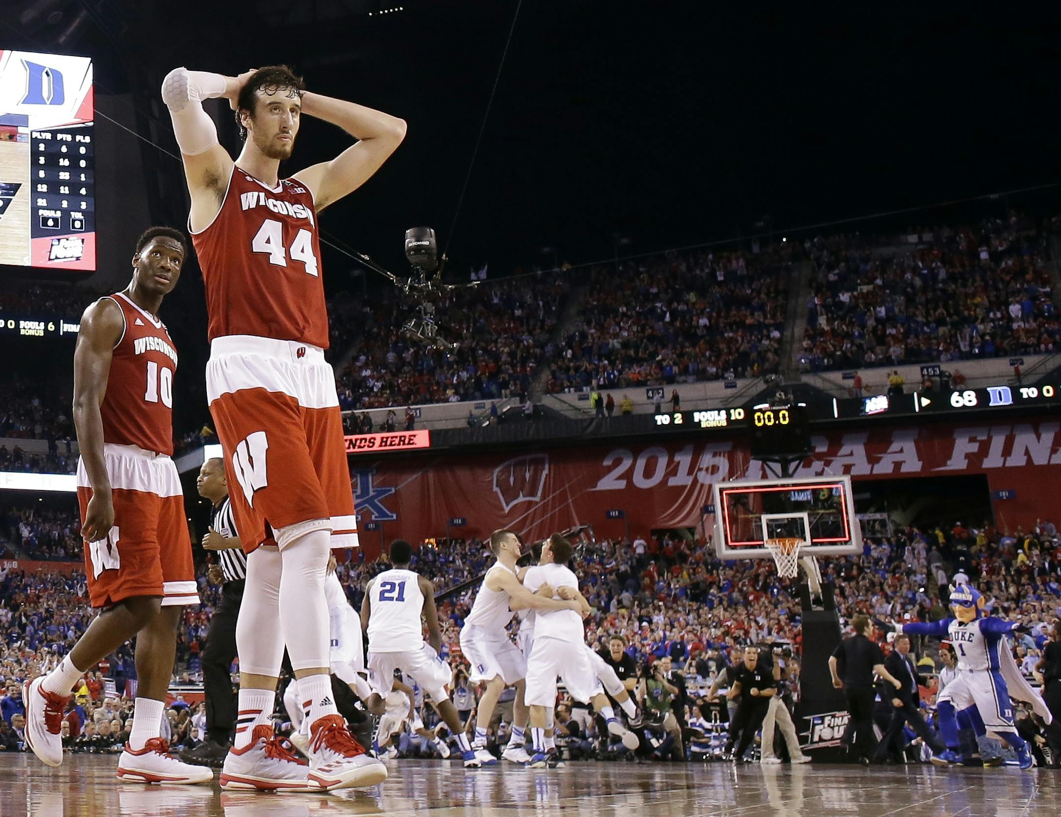 Wisconsin's Frank Kaminsky (44) and Nigel Hayes (10) walk off the court as Duke players celebrate their 68-63 victory over Wisconsin in the NCAA Final Four college basketball tournament championship game Monday, April 6, 2015, in Indianapolis. (AP Photo/Michael Conroy)
