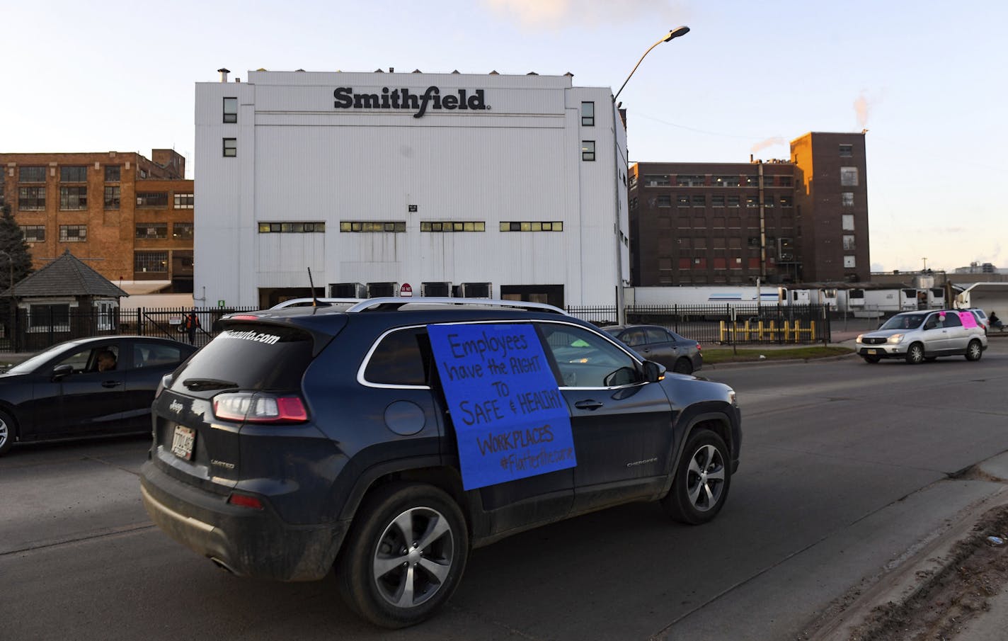 FILE - In this April 9, 2020, file photo, a car with a sign calling for a safe and healthy workplace drives past Smithfield Foods, Inc. in Sioux Falls, S.D., during a protest on behalf of employees after many workers complained of unsafe working conditions due to the COVID-19 outbreak. The plant was forced to close after nearly 300 of the plant&#x2019;s workers tested positive for the virus produces roughly 5% of the U.S. pork supply each day. (Erin Bormett/The Argus Leader via AP, File)