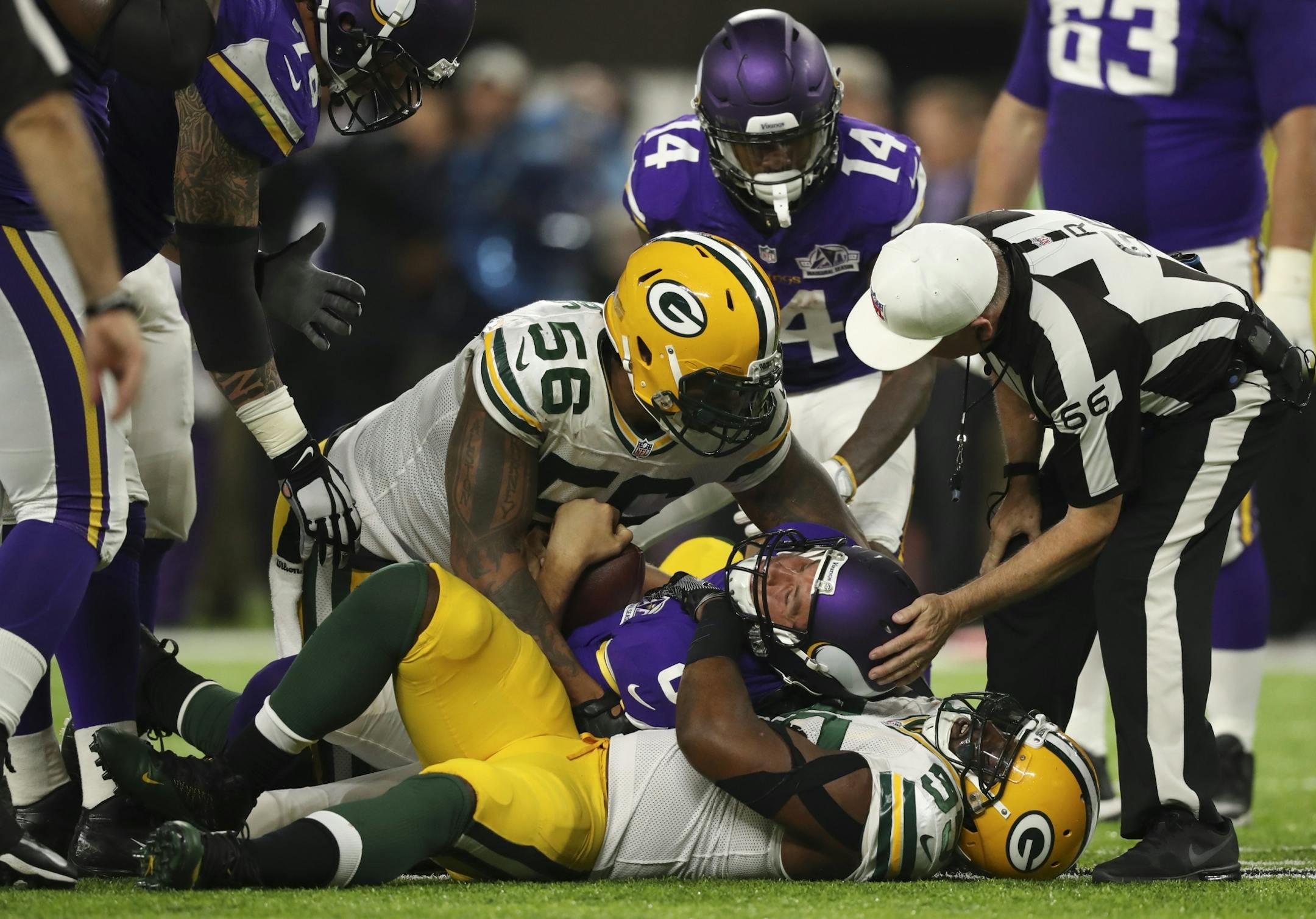 Vikings quarterback Sam Bradford (8) took a hard hit from Green Bay Packers outside linebacker Julius Peppers (56) and Green Bay Packers defensive end Datone Jones (95) late in the fourth quarter.