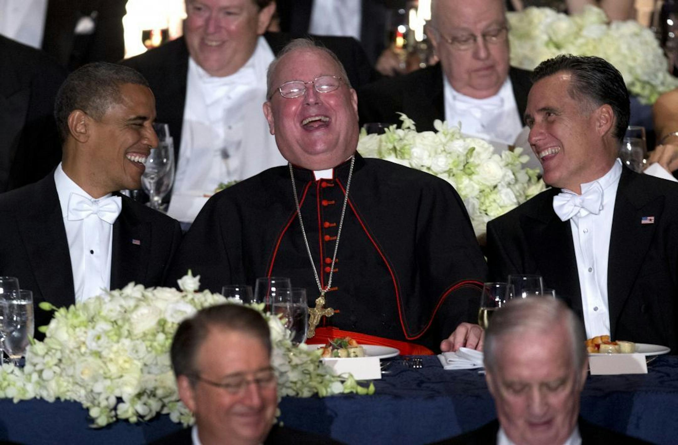 President Barack Obama, left, and Republican presidential candidate, former Massachusetts Gov. Mitt Romney, right, laugh with Cardinal Timothy Dolan during the Archdiocese of New York's 67th Annual Alfred. E. Smith Memorial Foundation Dinner, Thursday, Oct. 18, 2012, at the Waldorf Astoria Hotel in New York. Alfred E. Smith Memorial Foundation Dinner, a white-tie gala has been a required stop for politicians since the end of World War II. In keeping with tradition, candidates prepare humorous fa
