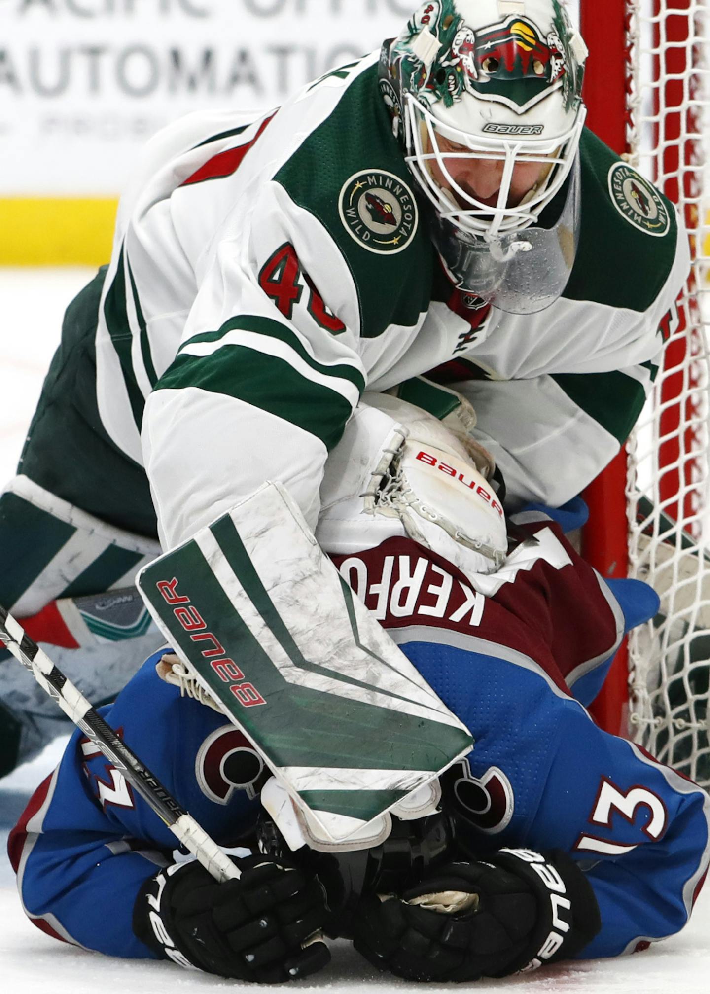 Minnesota Wild goaltender Devan Dubnyk, top, pushes Colorado Avalanche center Alexander Kerfoot to the ice after Kerfoot crashed into Dubnyk during the third period of an NHL hockey game Saturday, Jan. 6, 2018, in Denver. The Avalanche won 7-2. (AP Photo/David Zalubowski)