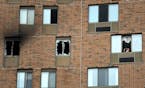A person peers out a window on the 11th floor where an overnight fire in the a high-rise Wilder Park Condominiums in St. Paul sent one person to the h