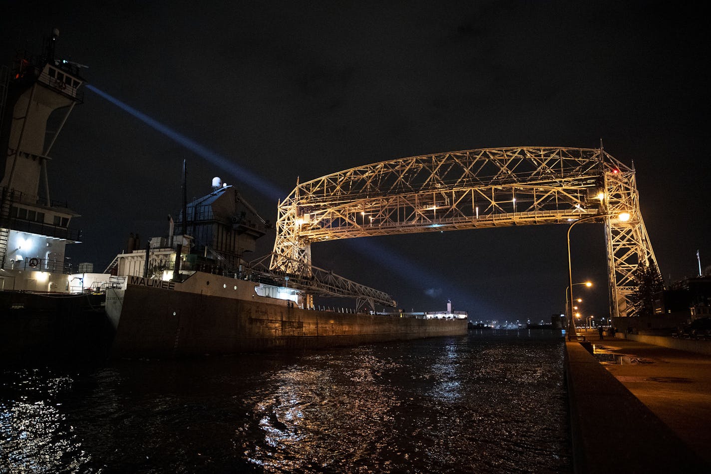 The Victory illuminated its spotlight as it pushed the barge Maumee into the Duluth Harbor under the aerial lift bridge on Tuesday night.