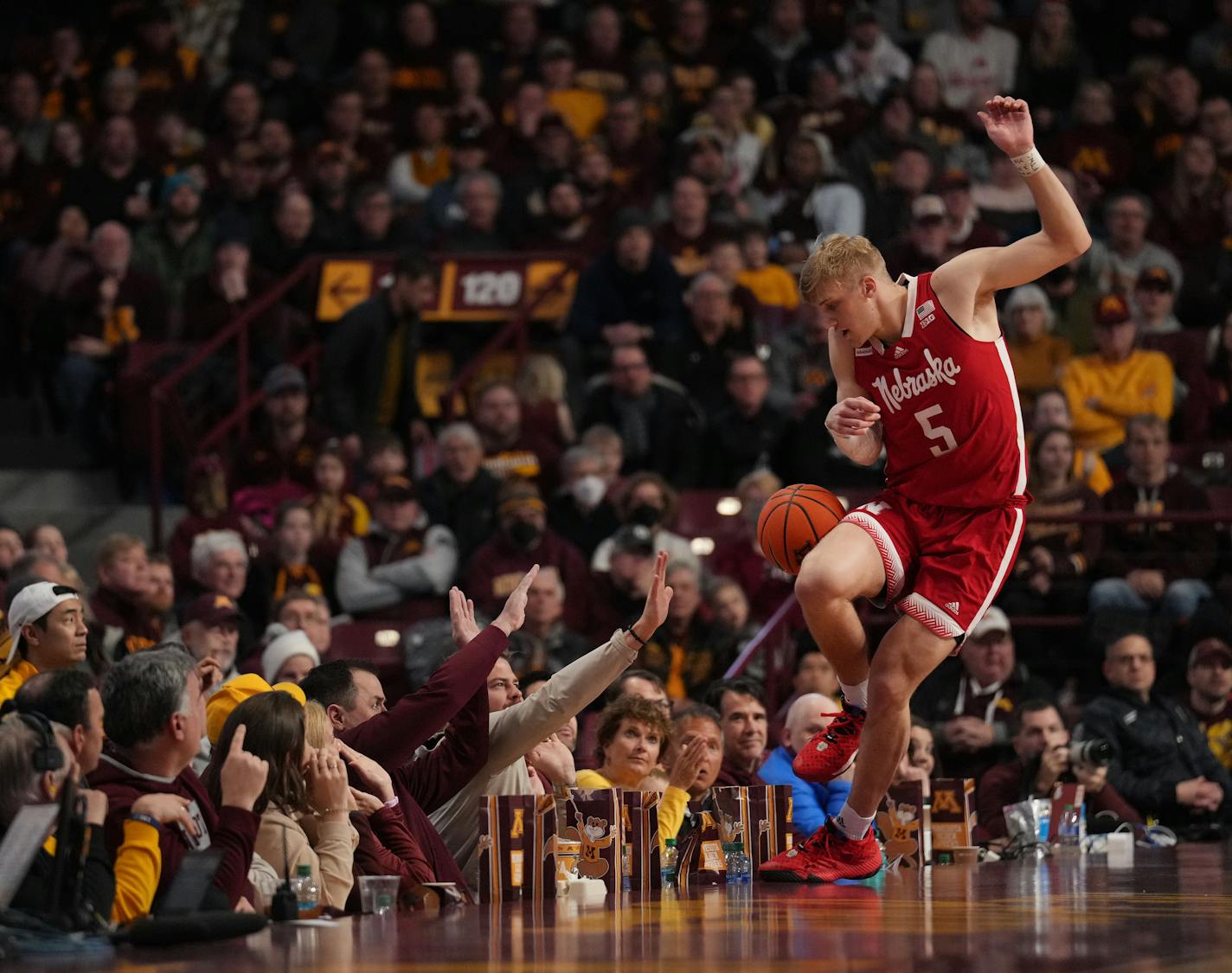 Fans reach out to brace themselves as Nebraska Cornhuskers guard Sam Griesel (5) attempts to avoid touching the ball as it bounces out of bounds in the second half at Williams Arena in Minneapolis, Minn., on Saturday, Jan. 7, 2023.