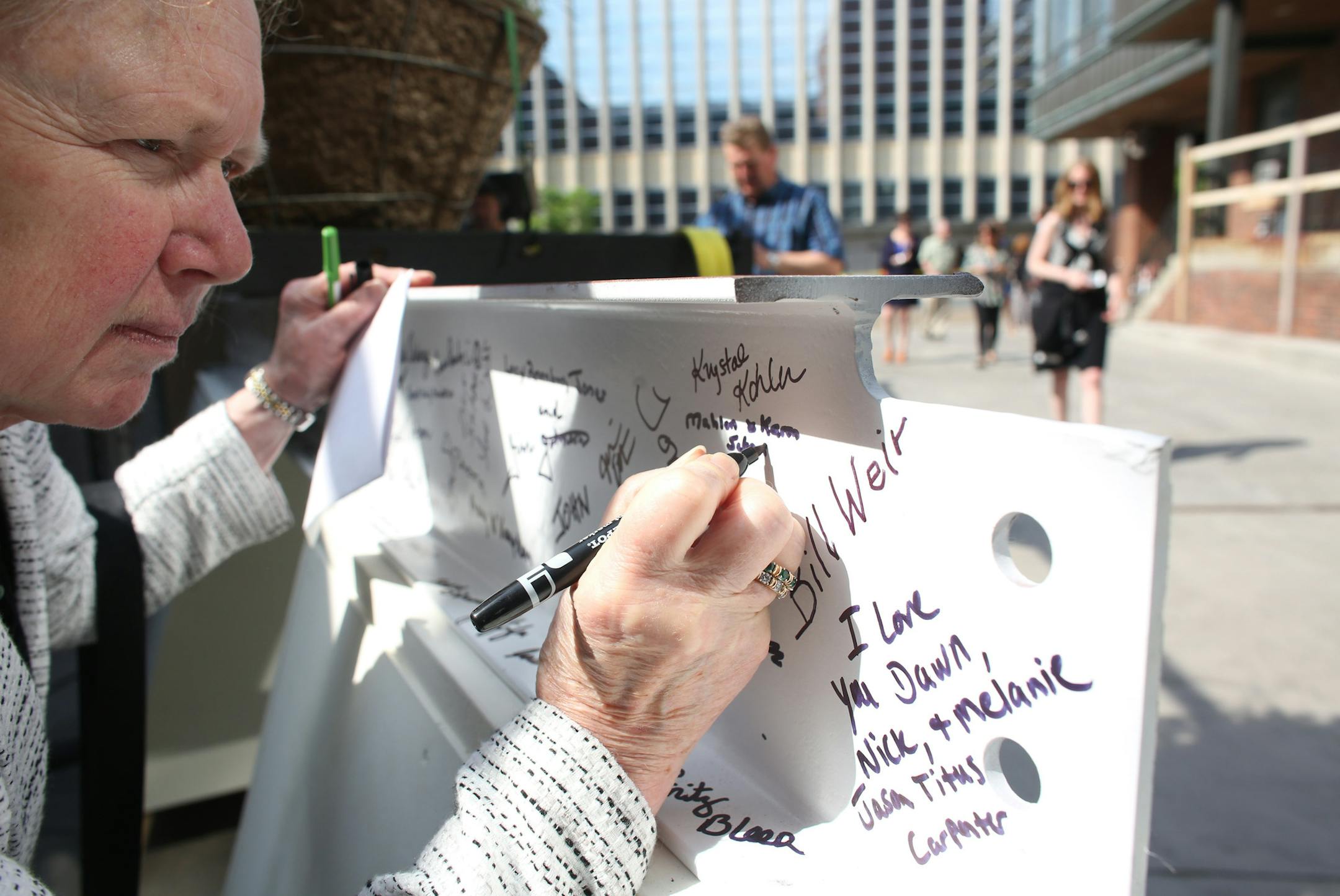 Lucy Jones signed the names of donors Mahlen and Karen Schneider, who couldn't make it to the ceremony, to the beam that will go at the top of the new structure at the Ordway Center.