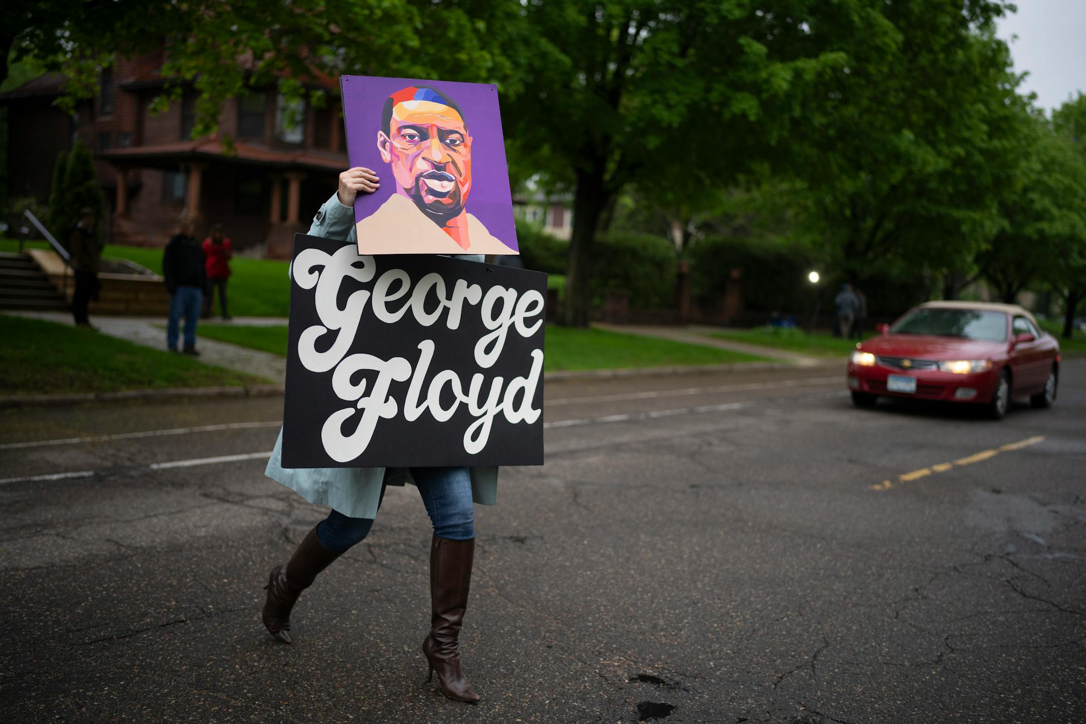 A woman carrying George Floyd signs crossed Summit Ave. to join a small group that swelled to about 60 people gathered on the sidewalk in front of the Governor's Residence to honor the memory of George Floyd and to call for action.